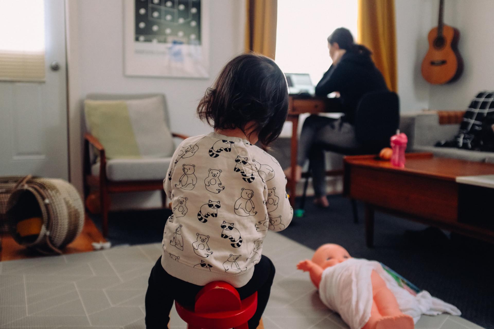 Mother working from home while daughter plays behind her