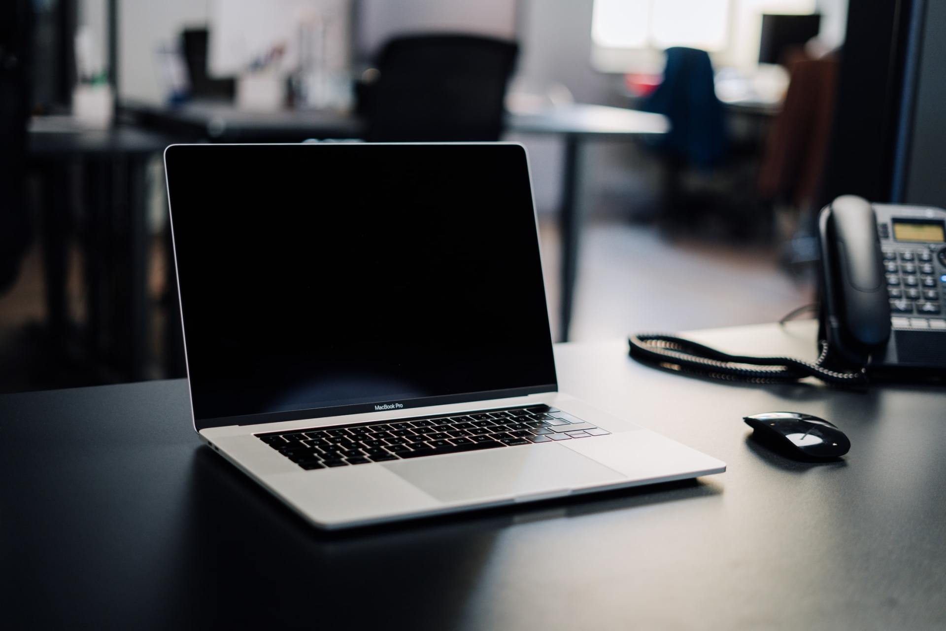 A laptop is open on a desk next to a phone
