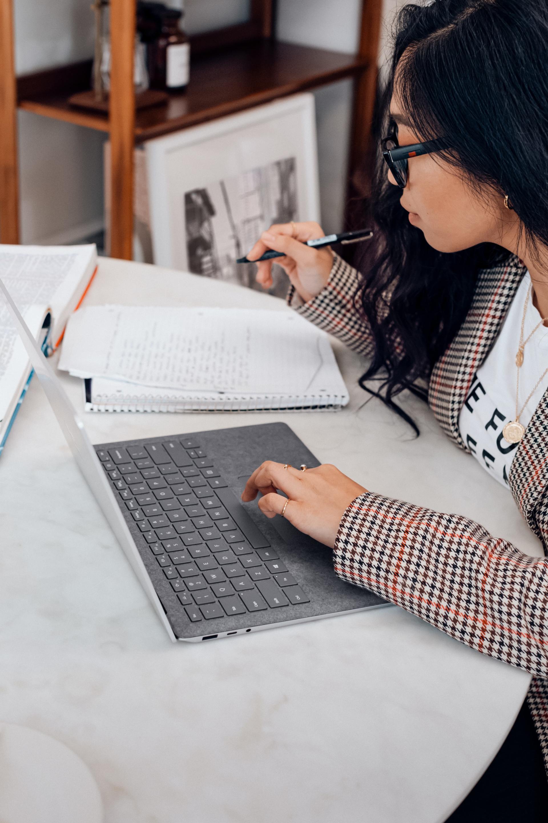 Una mujer está sentada en una mesa utilizando una computadora portátil.