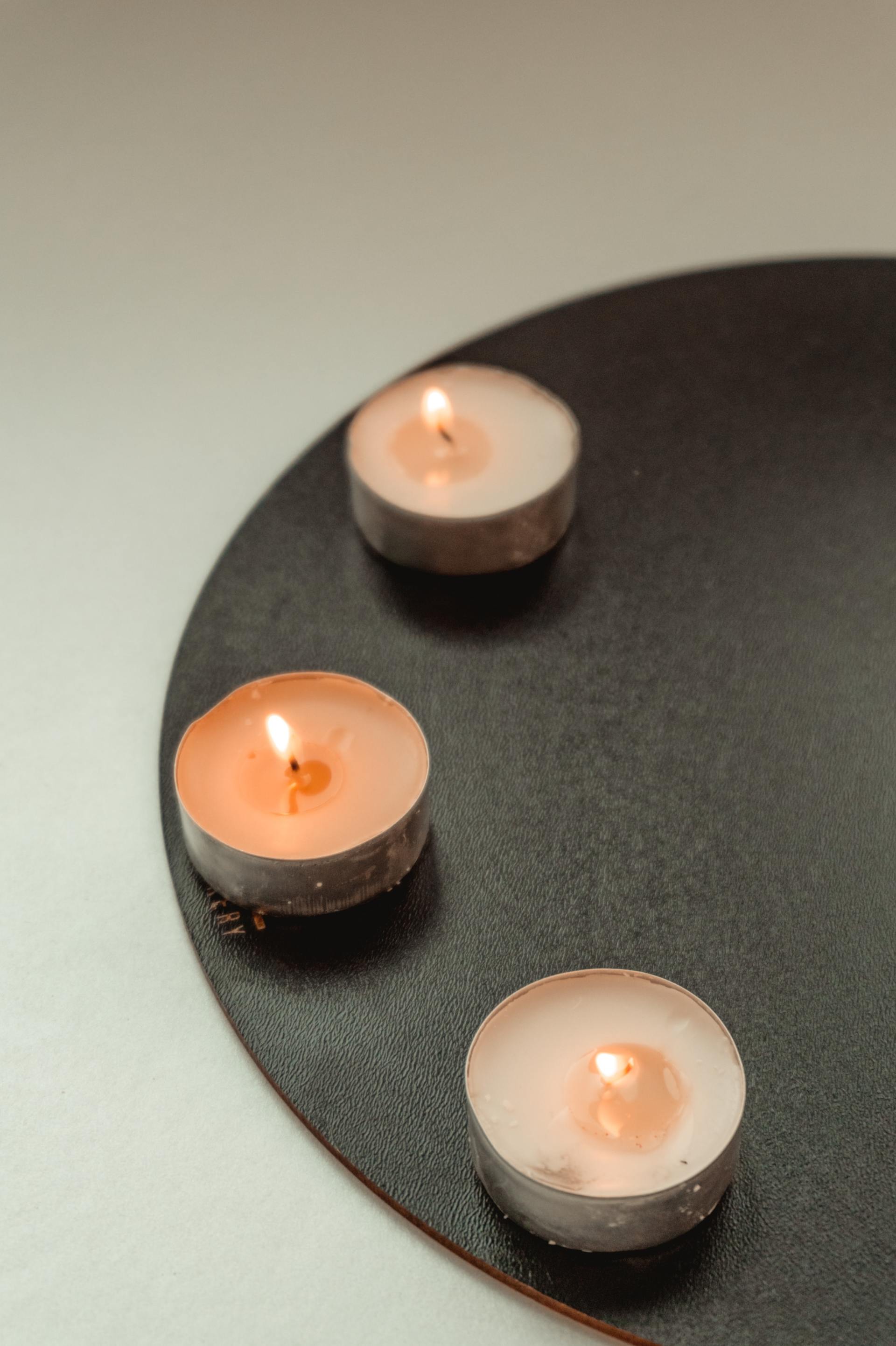 Three small candles are sitting on a black plate.