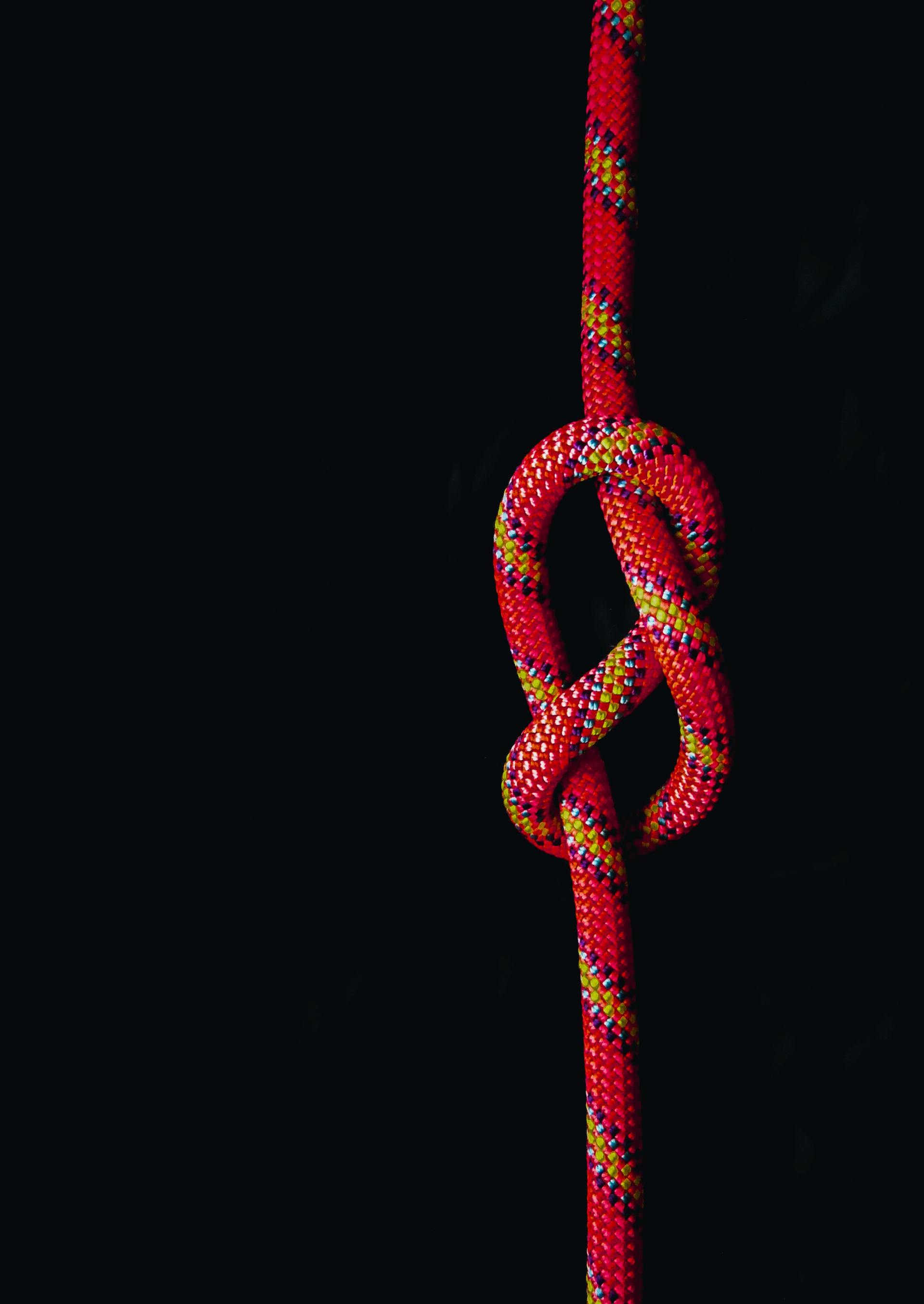 A red rope with a knot in the middle on a black background.