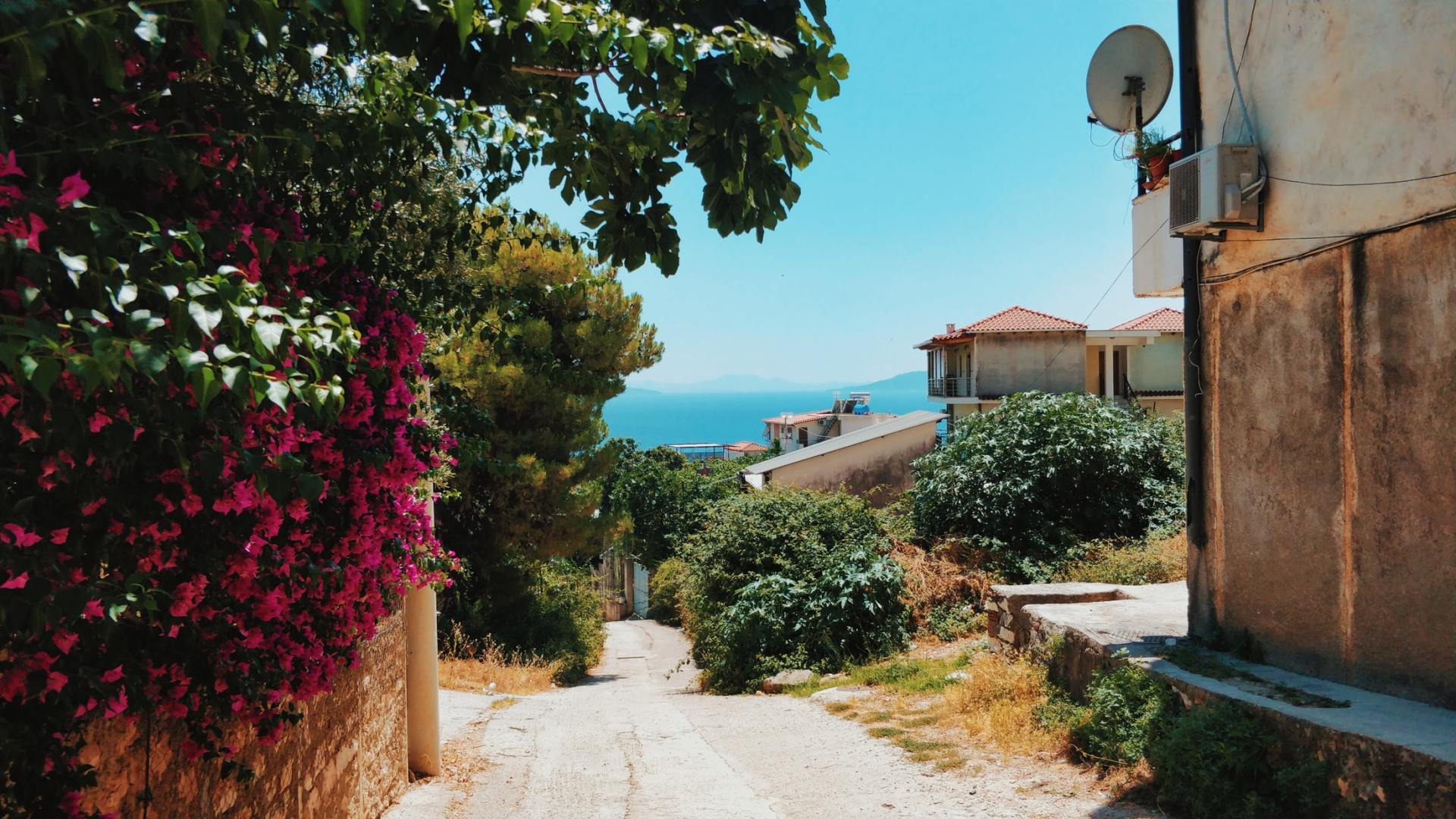 A narrow street with a satellite dish on the side of a building.