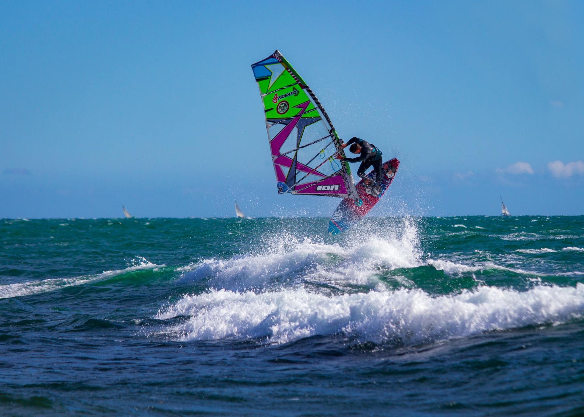 Uma pessoa está praticando windsurf em uma onda no oceano.