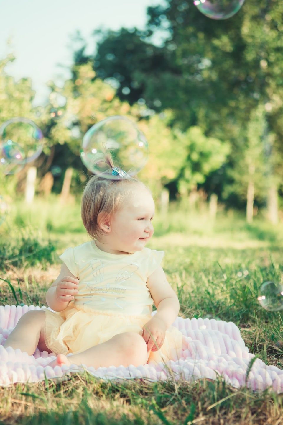 baby sitting outside with bubble on head