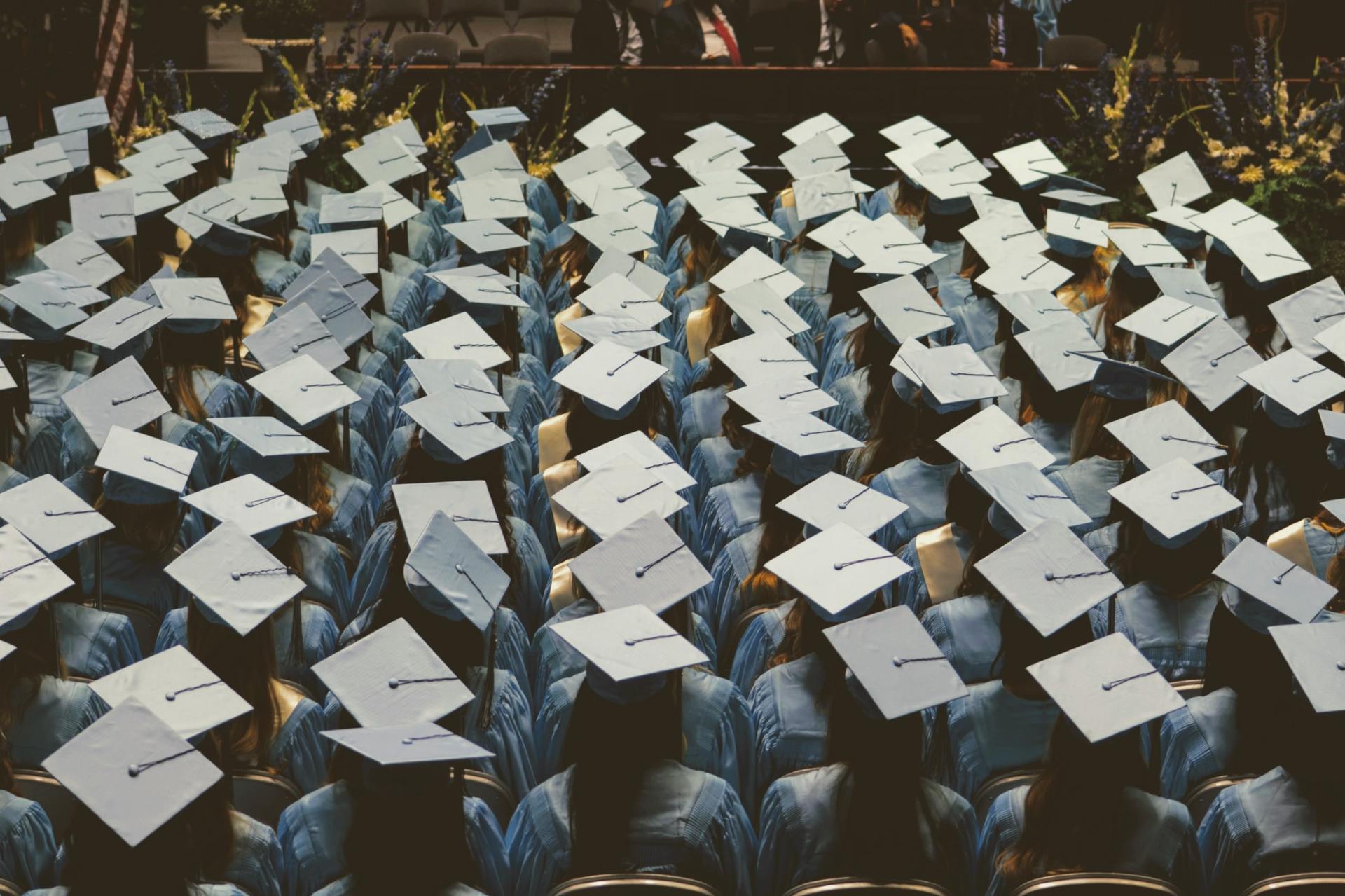 A row of graduation caps are sitting on top of each other in a stadium.