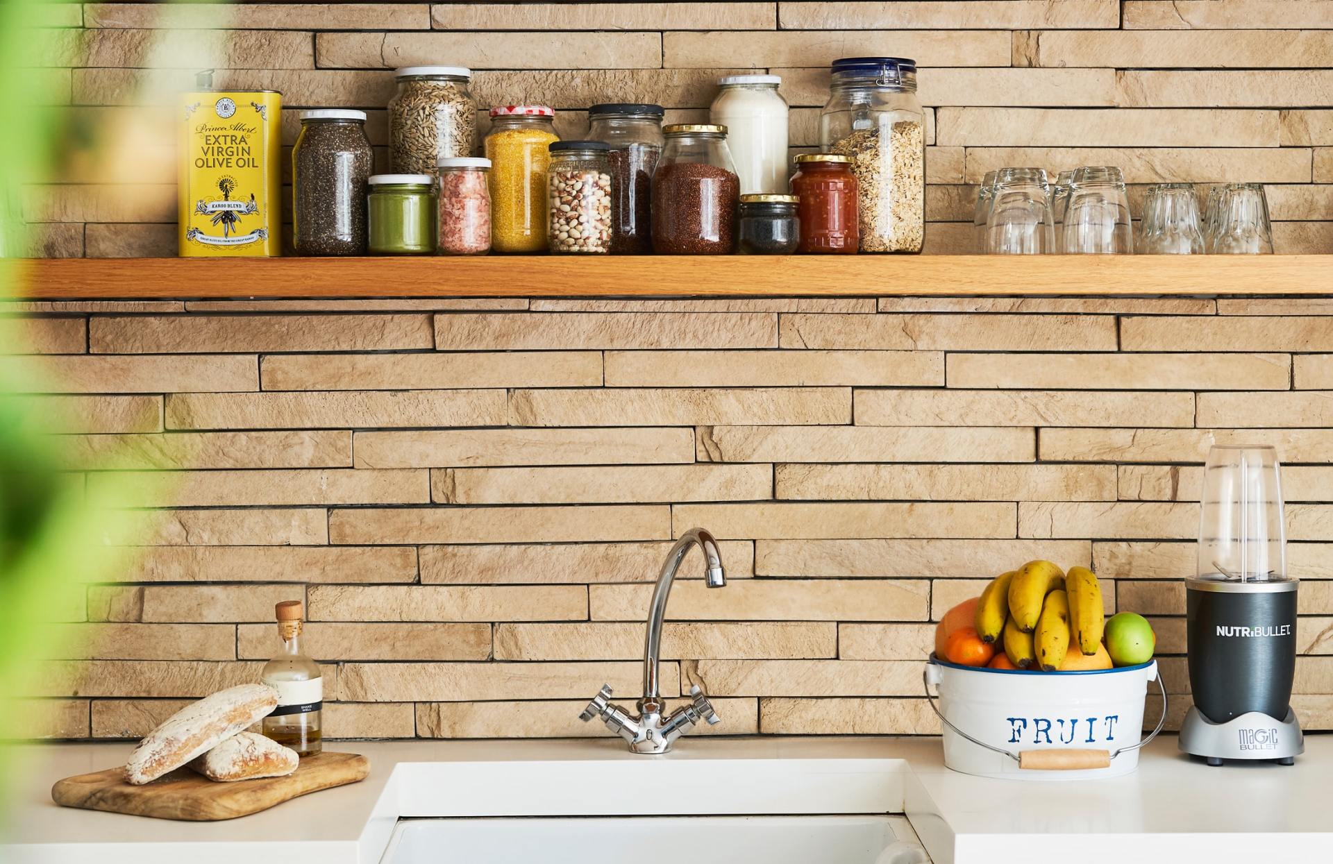 A kitchen with a brick wall , a sink , and a blender.