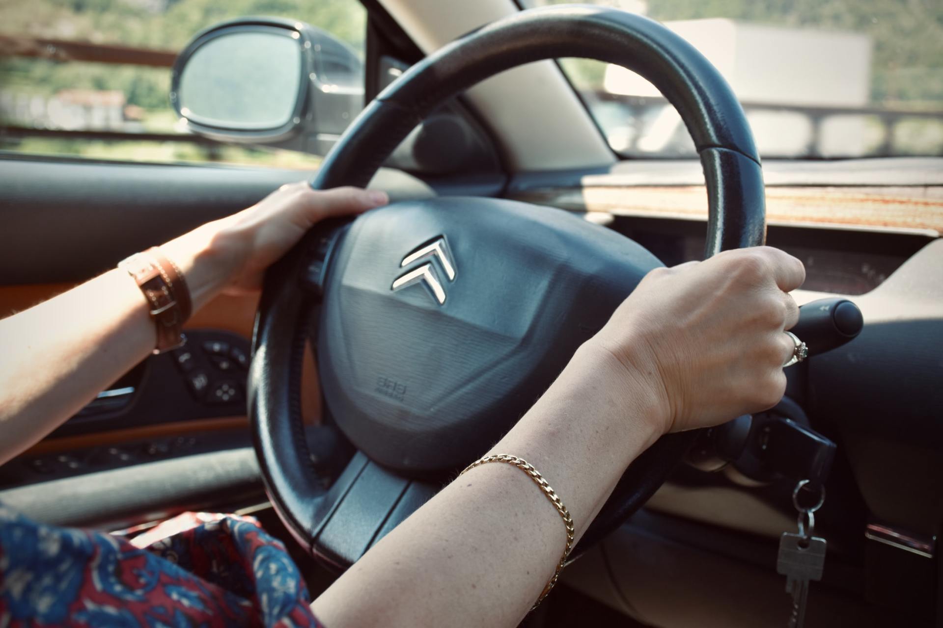 Woman holding a car's steering wheel.