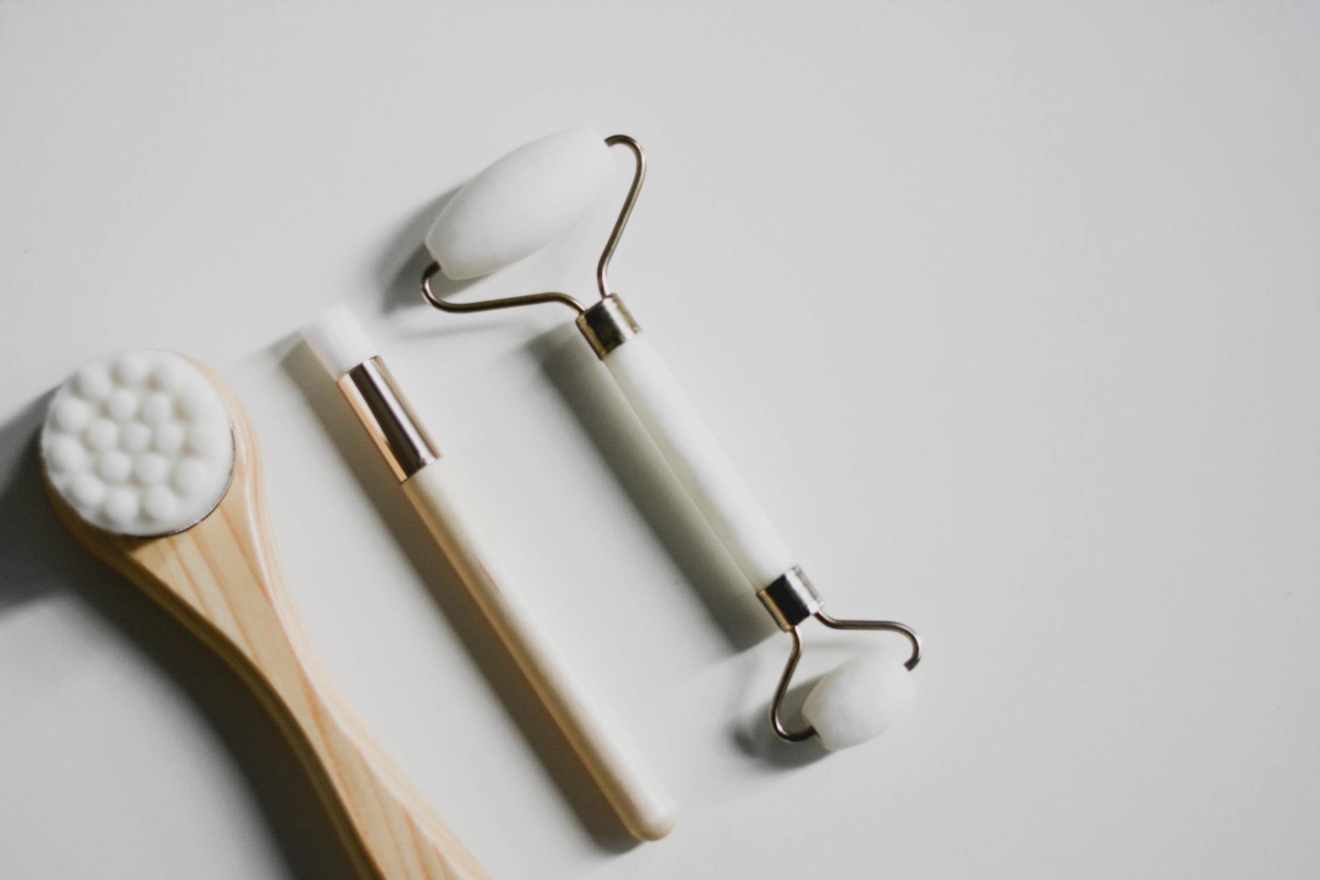 A facial roller and a brush are on a white surface.