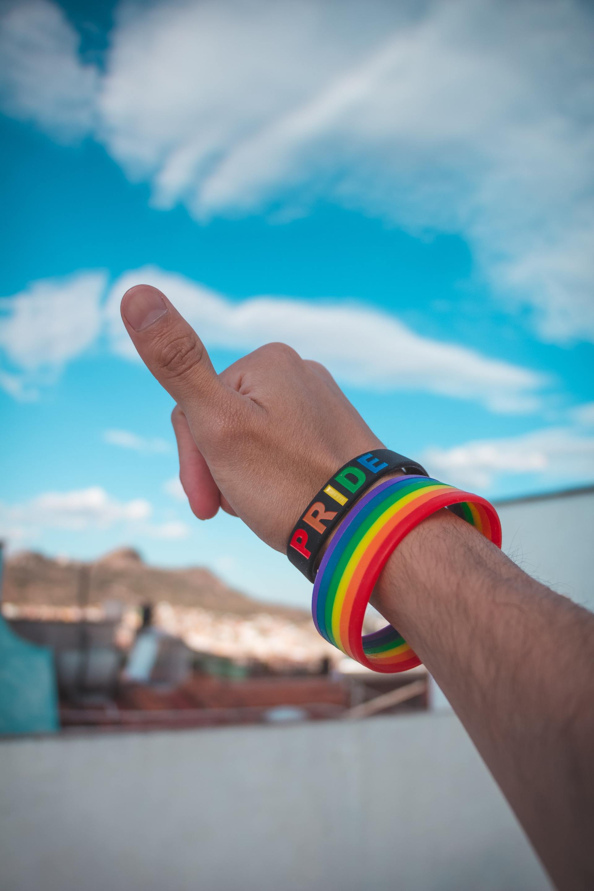 A person wearing a rainbow wristband with the word pride on it
