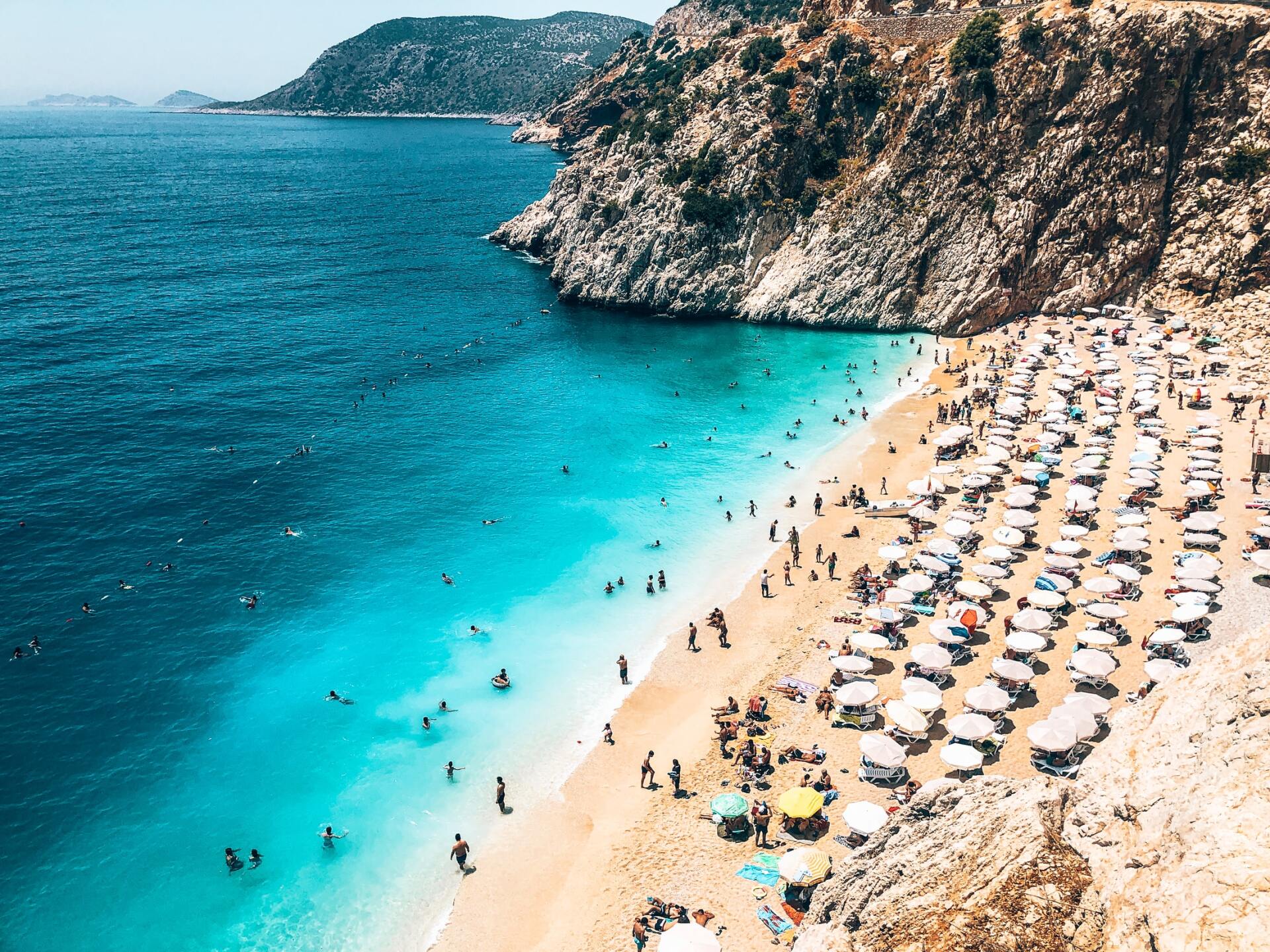 A beach filled with people and umbrellas on a sunny day.