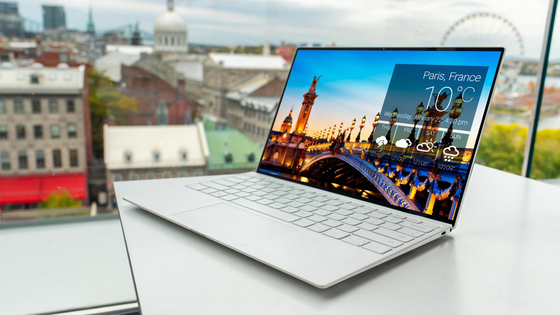 A laptop computer is sitting on a table in front of a window.