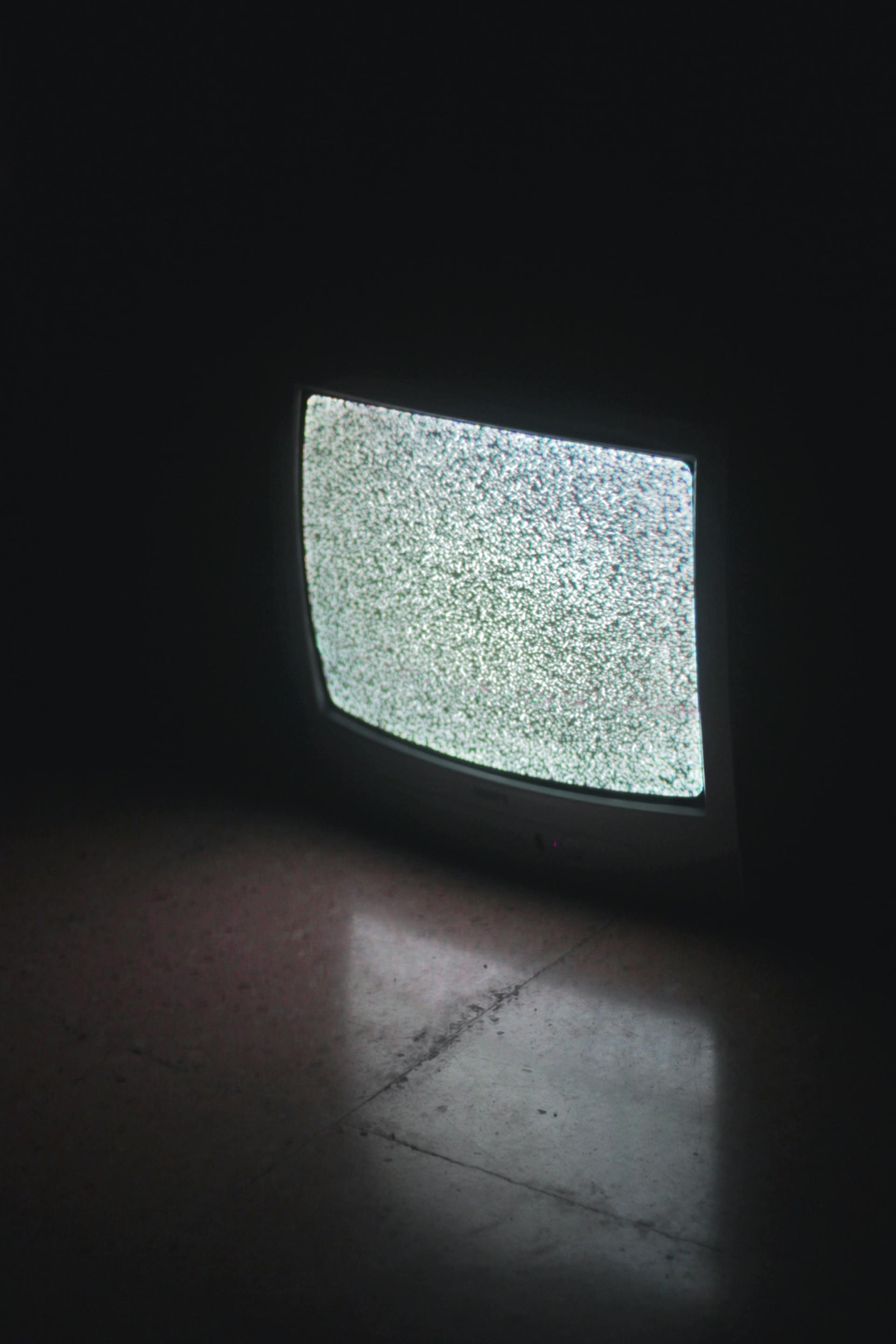 A television is sitting on the floor in a dark room.