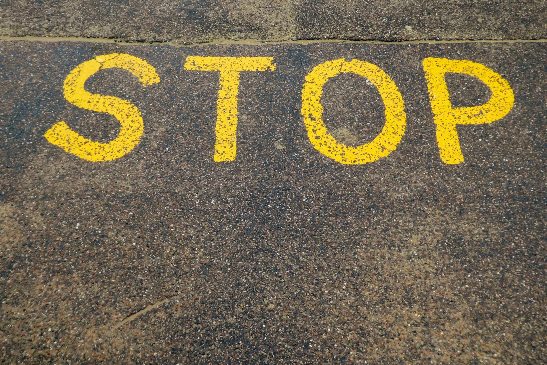 the word stop is painted in yellow on the ground