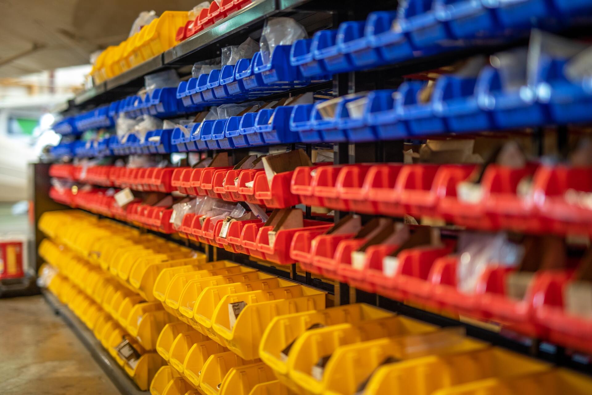 a shelf filled with red , yellow and blue plastic bins .