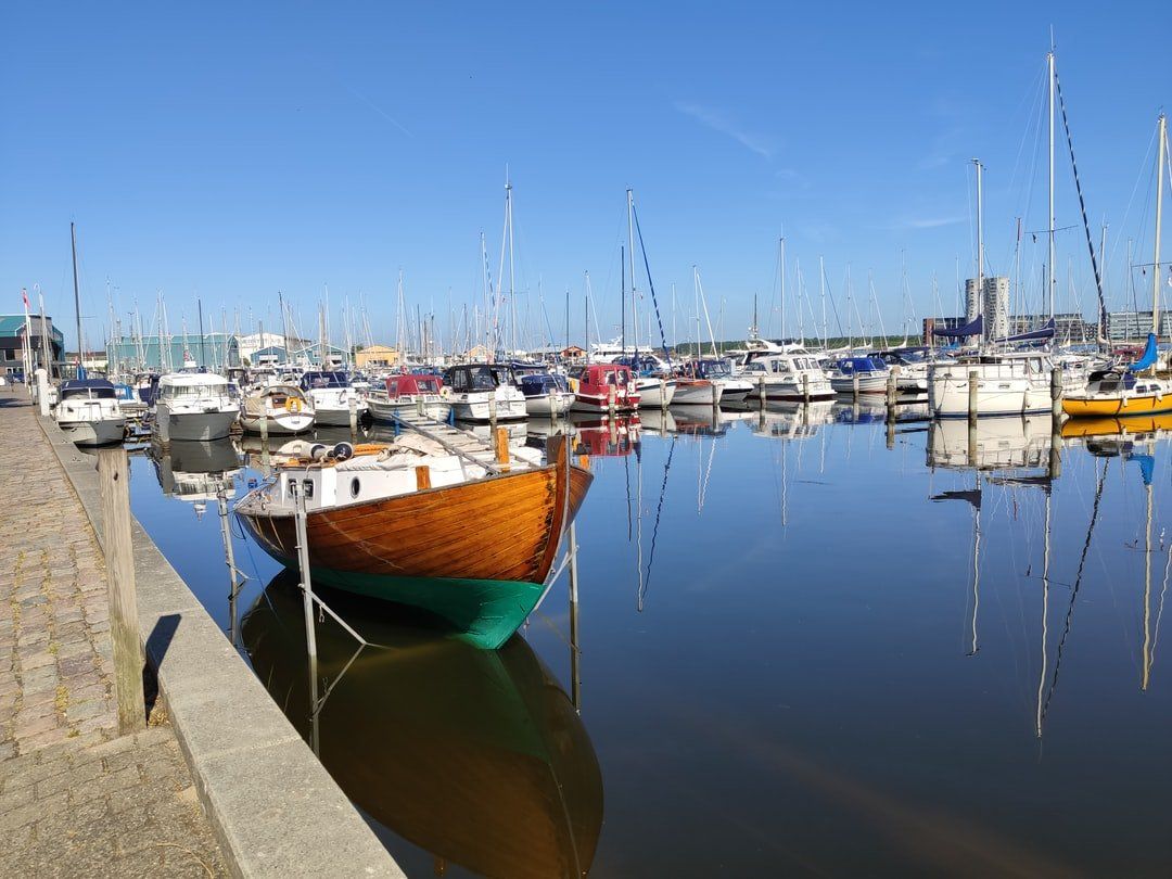 En gruppe både ligger til kaj i en havn på en solskinsdag.