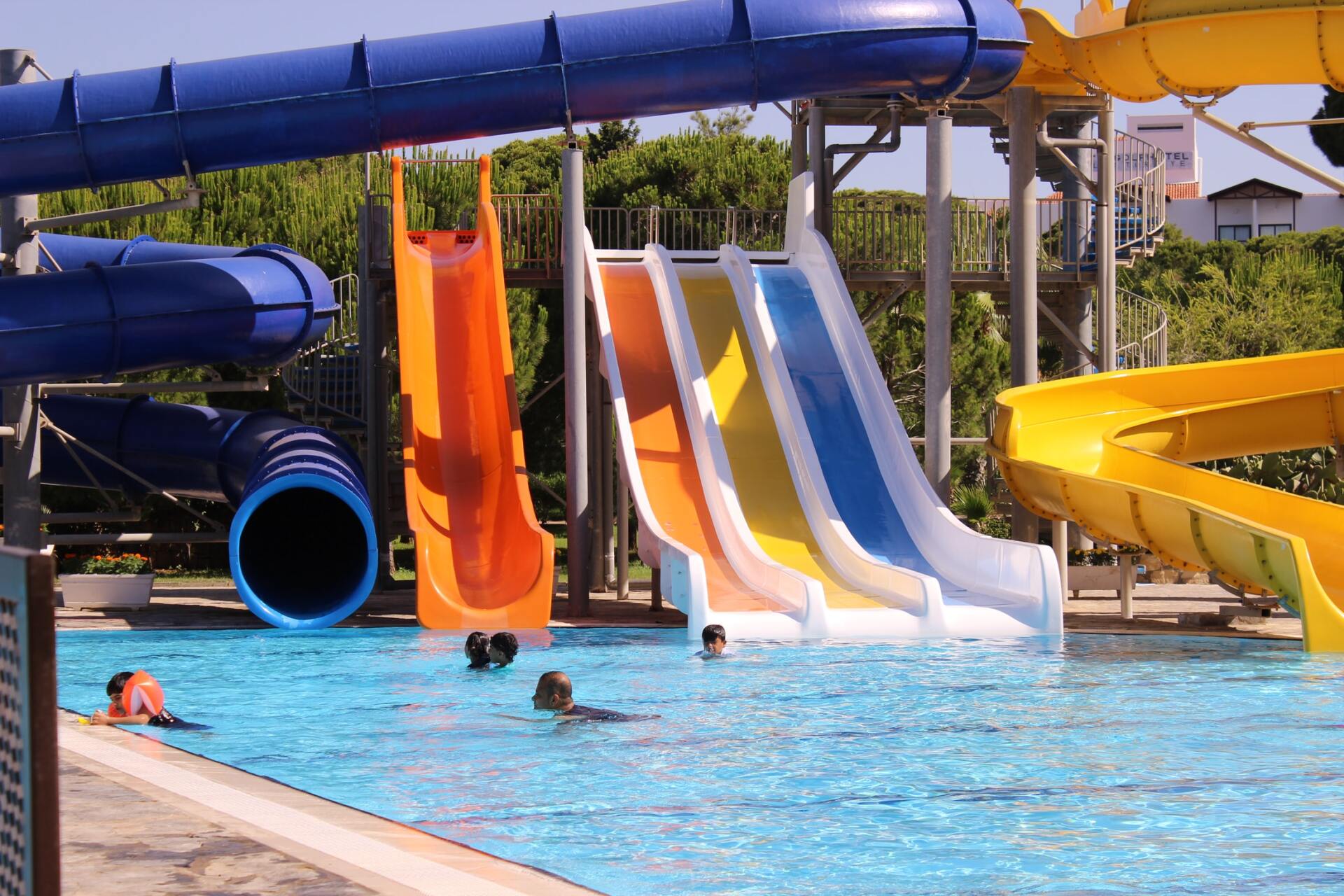 People are swimming in a pool with water slides in the background
