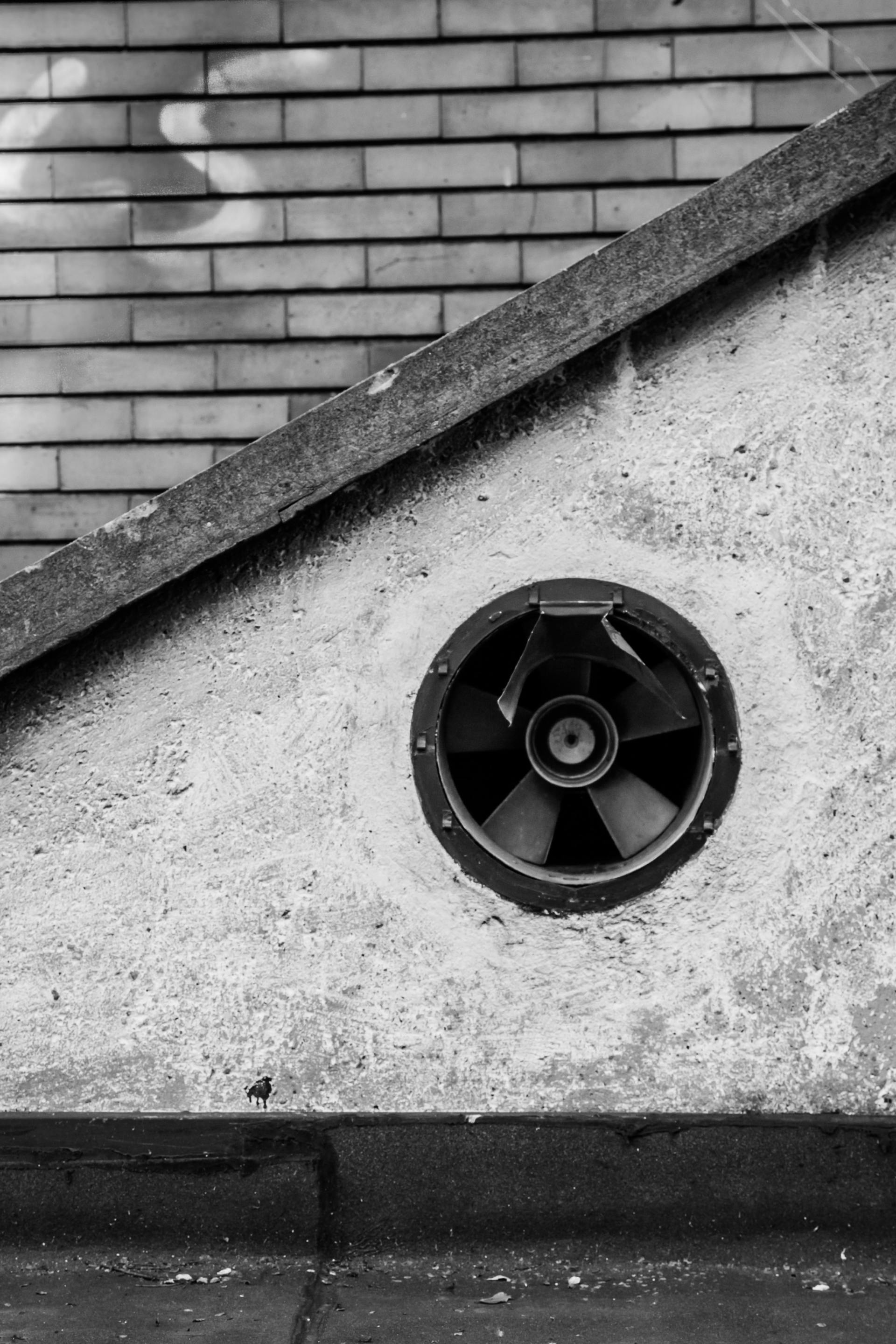 A black and white photo of a fan on the side of a building