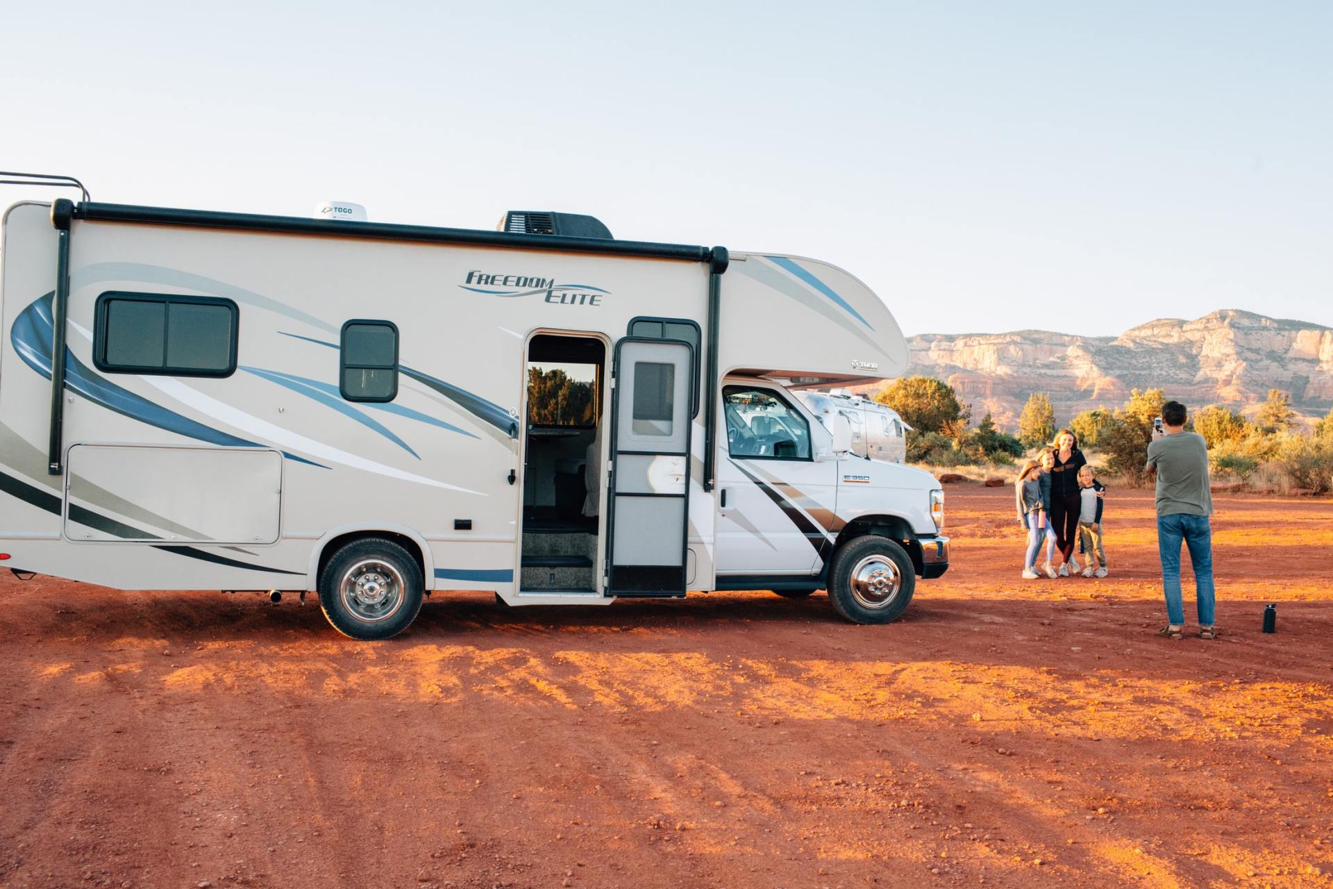 A family taking a picture in front of a RV in the Desert