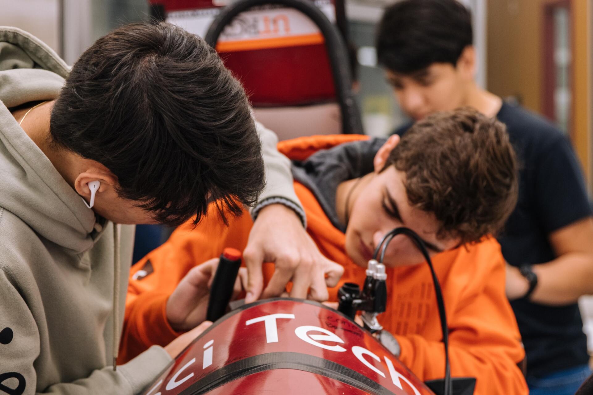 A group of young men are working on a red vehicle.