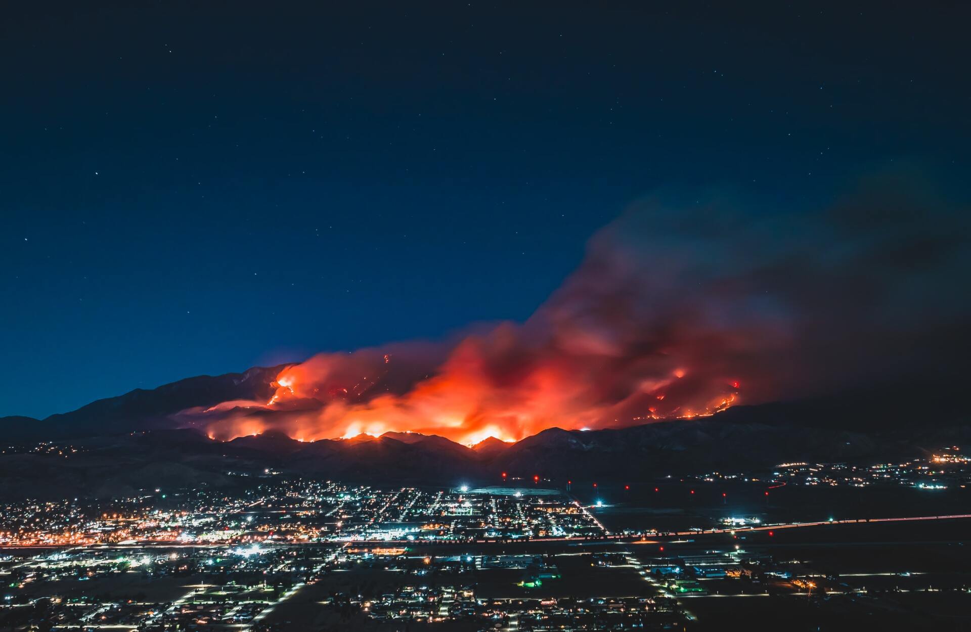 Photo of fire on hillside above city at night.