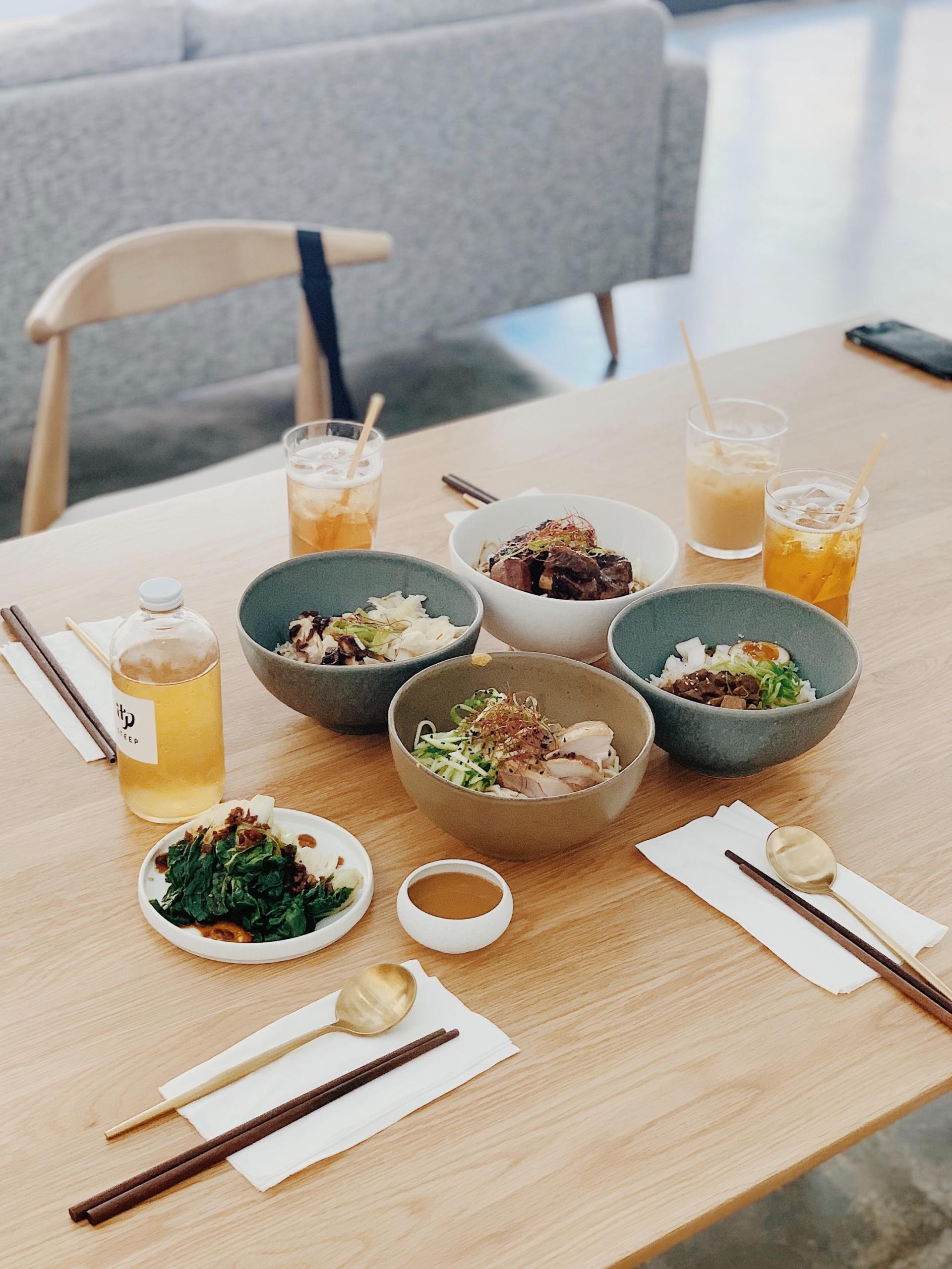 A wooden table topped with bowls of food and drinks.