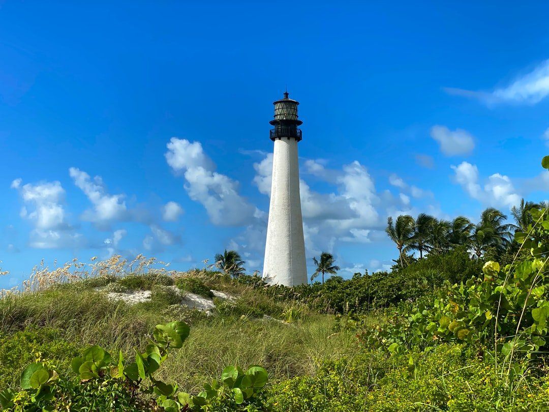 A lighthouse is sitting on top of a grassy hill.