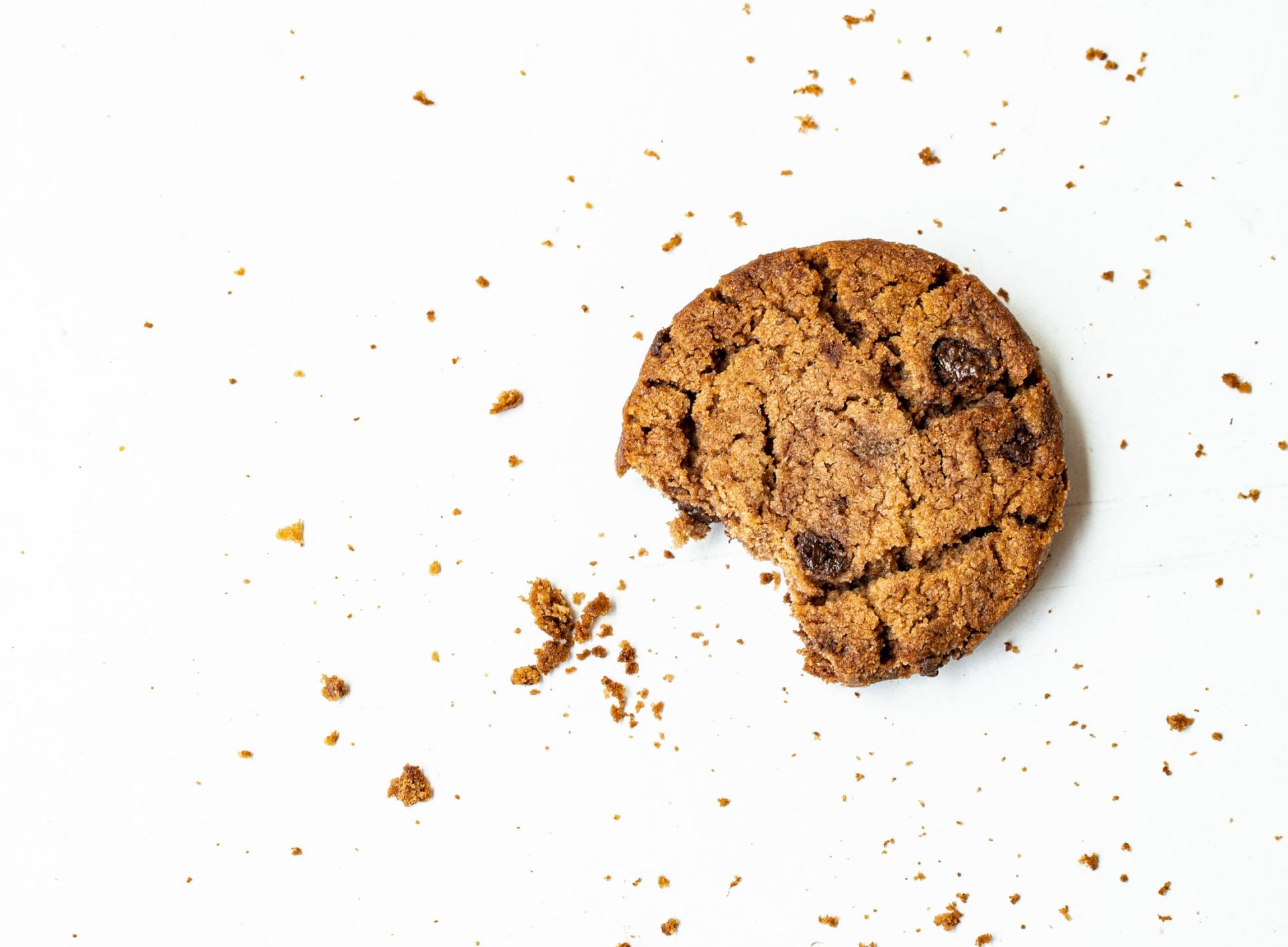 a chocolate chip cookie with a bite taken out of it on a white surface .