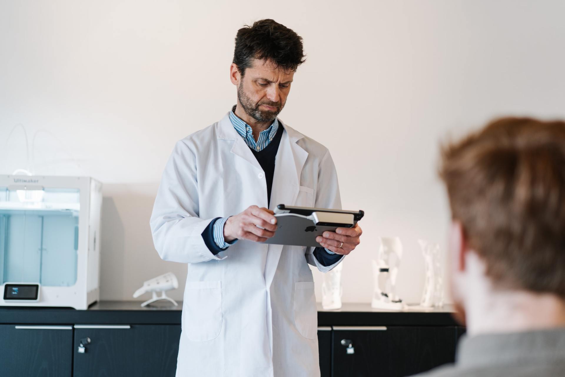 Un médico sostiene una tableta delante de un paciente.