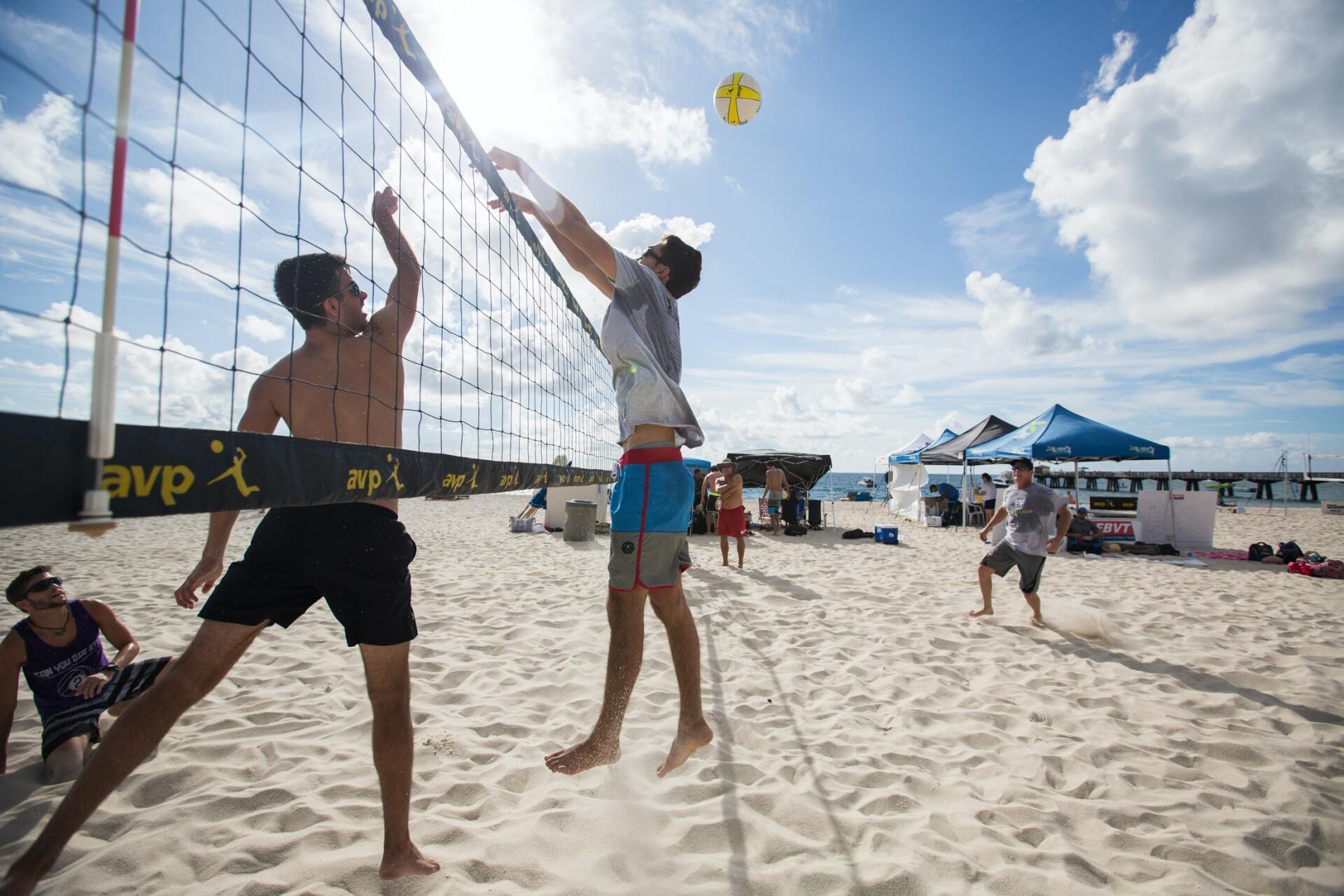 A group of young men are playing volleyball on the beach.