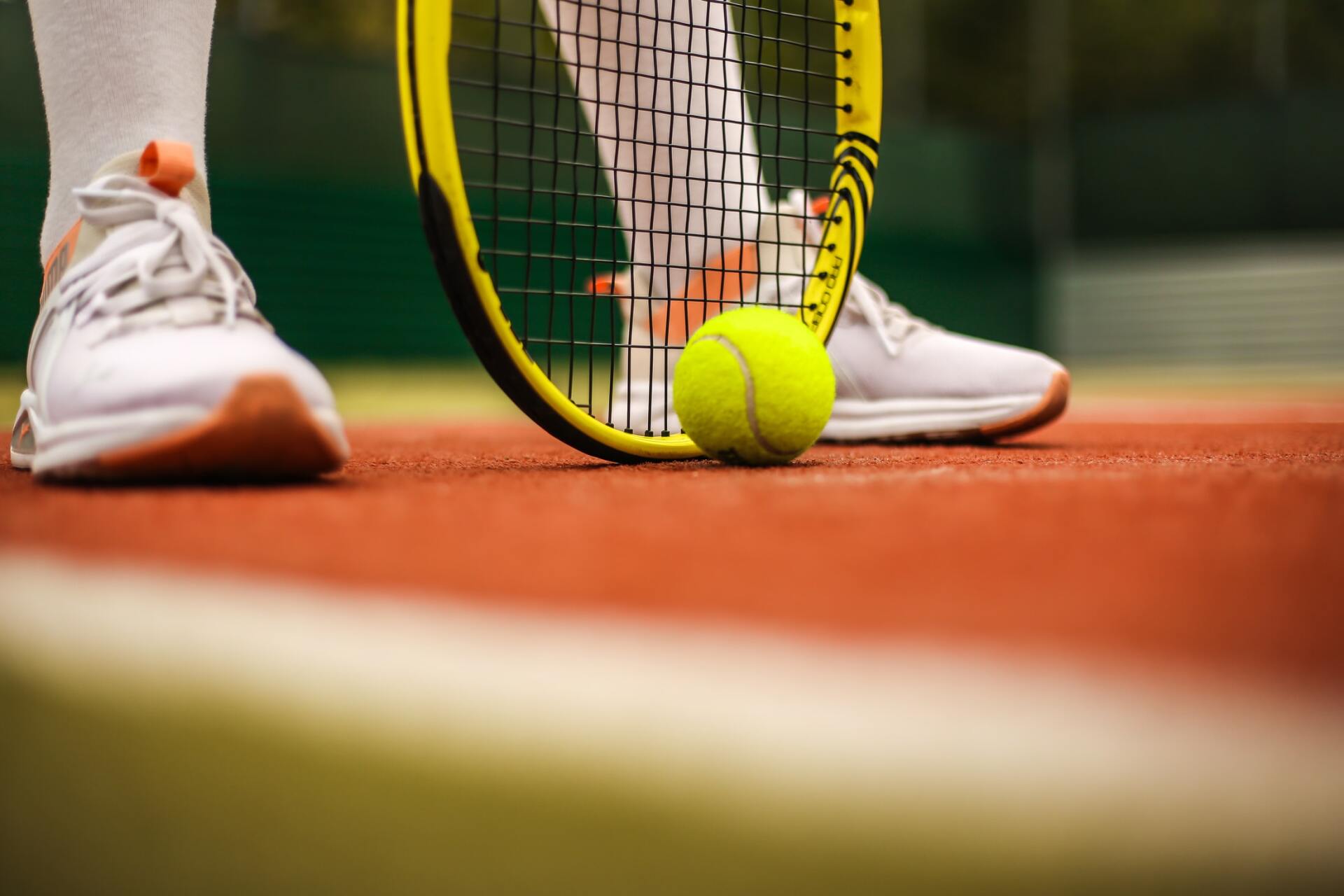 A person is holding a tennis racquet and a tennis ball on a tennis court.
