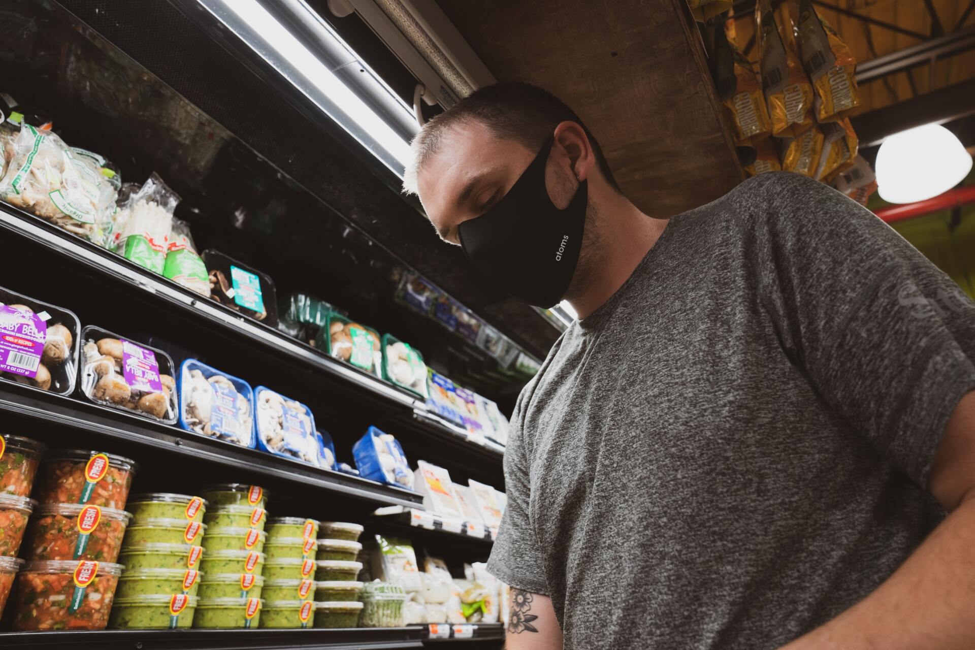 A man wearing a mask is shopping in a grocery store.