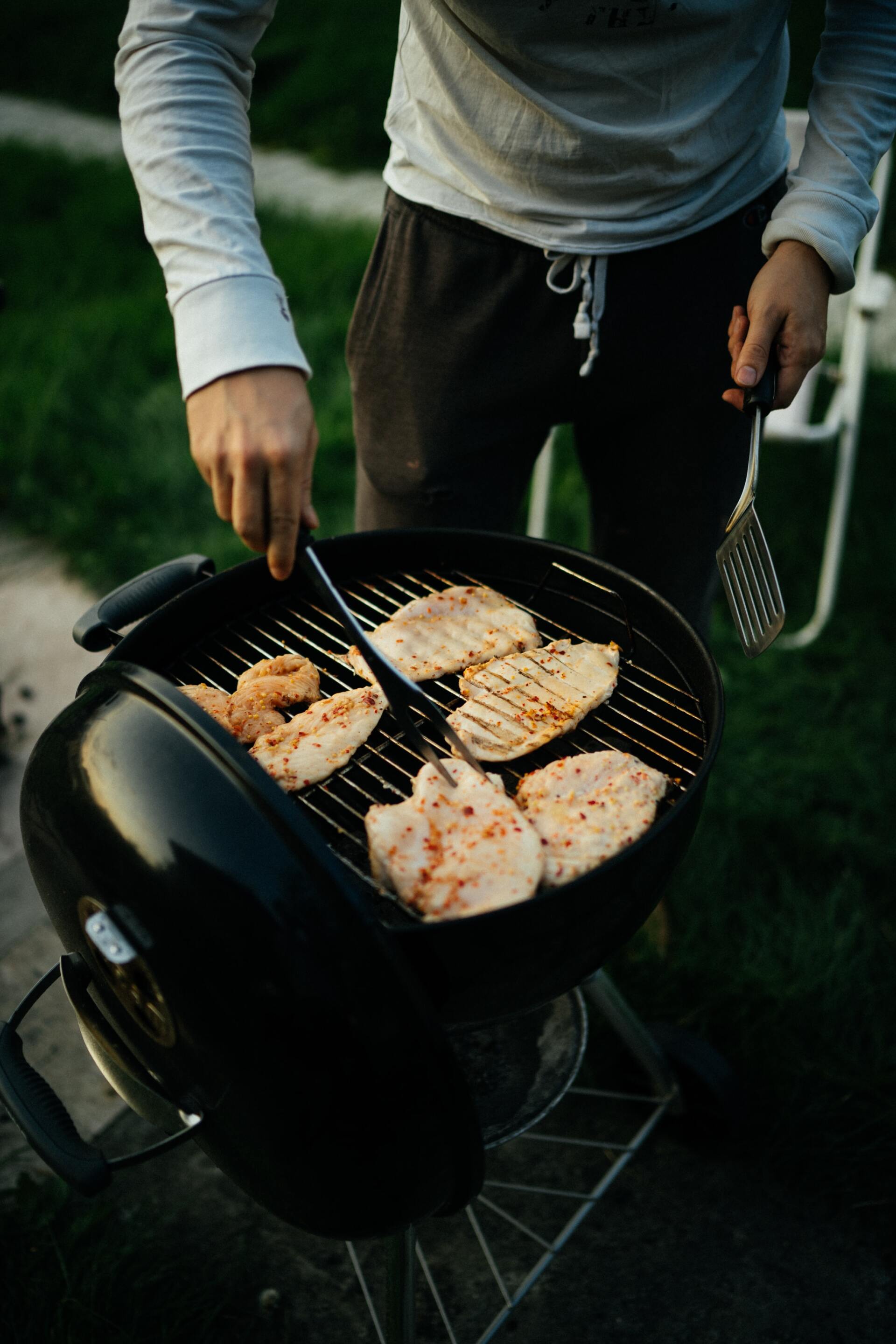 A man is grilling meat on a barbecue grill.