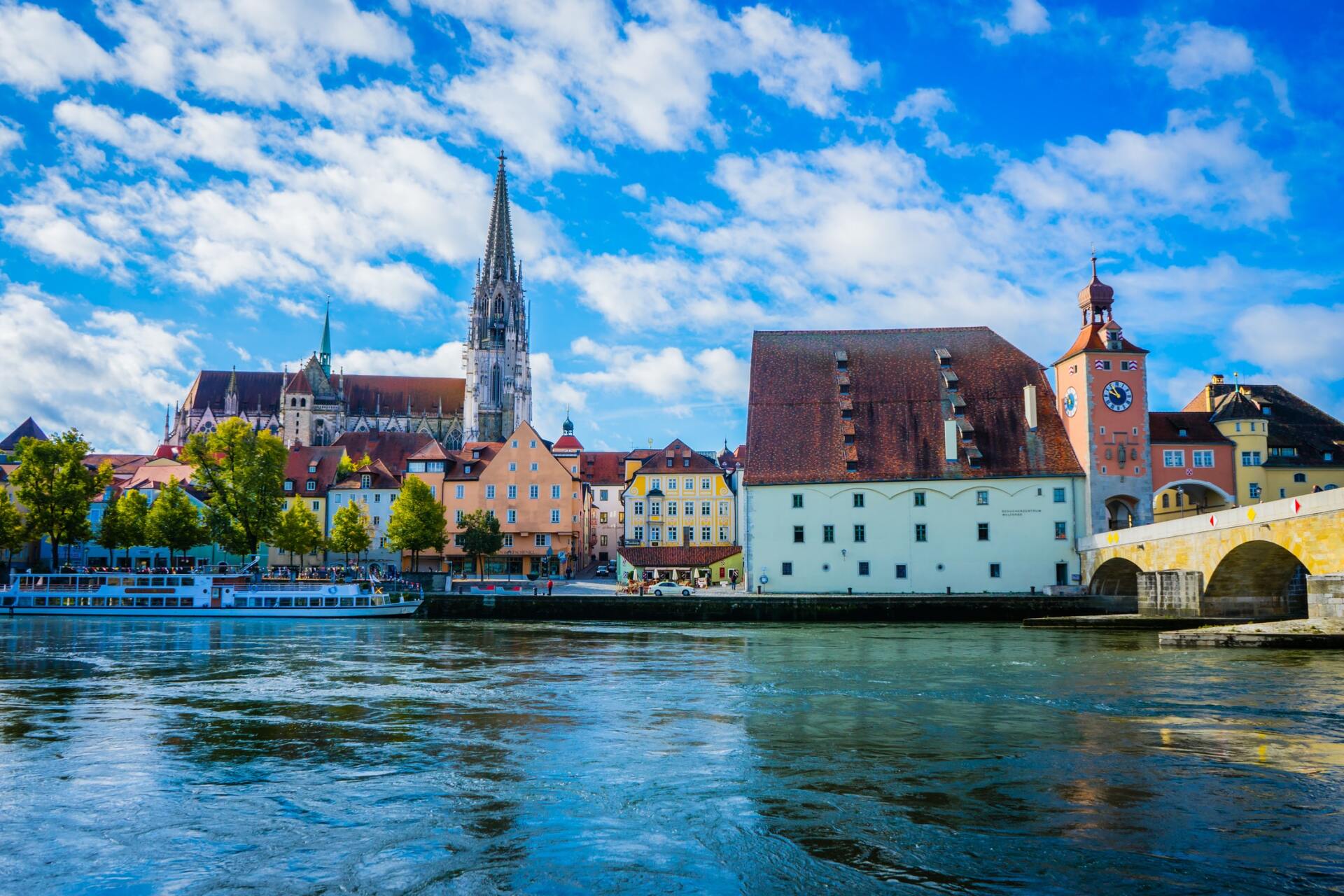 eine Stadt am Ufer eines Flusses mit einer Brücke im Vordergrund.