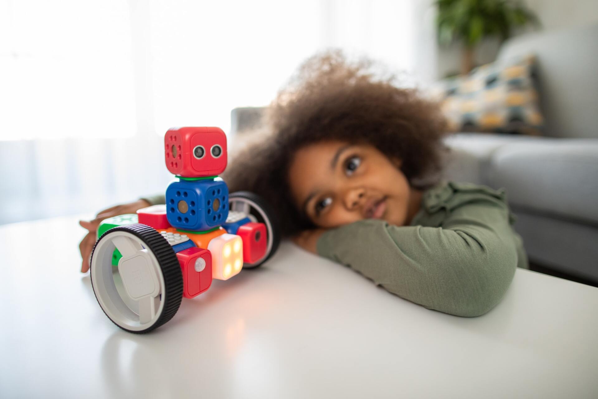 A little girl is playing with a toy robot on a table.