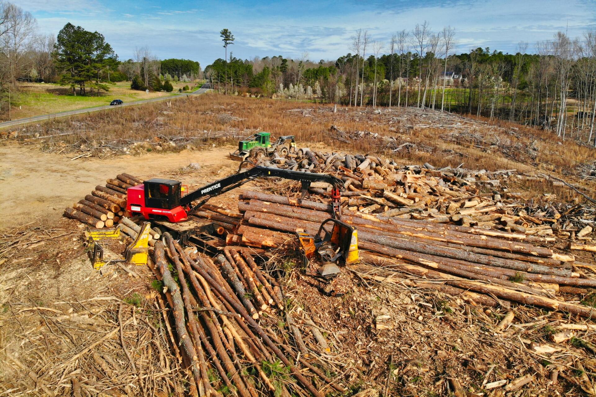 An aerial view of a large pile of logs in a field.