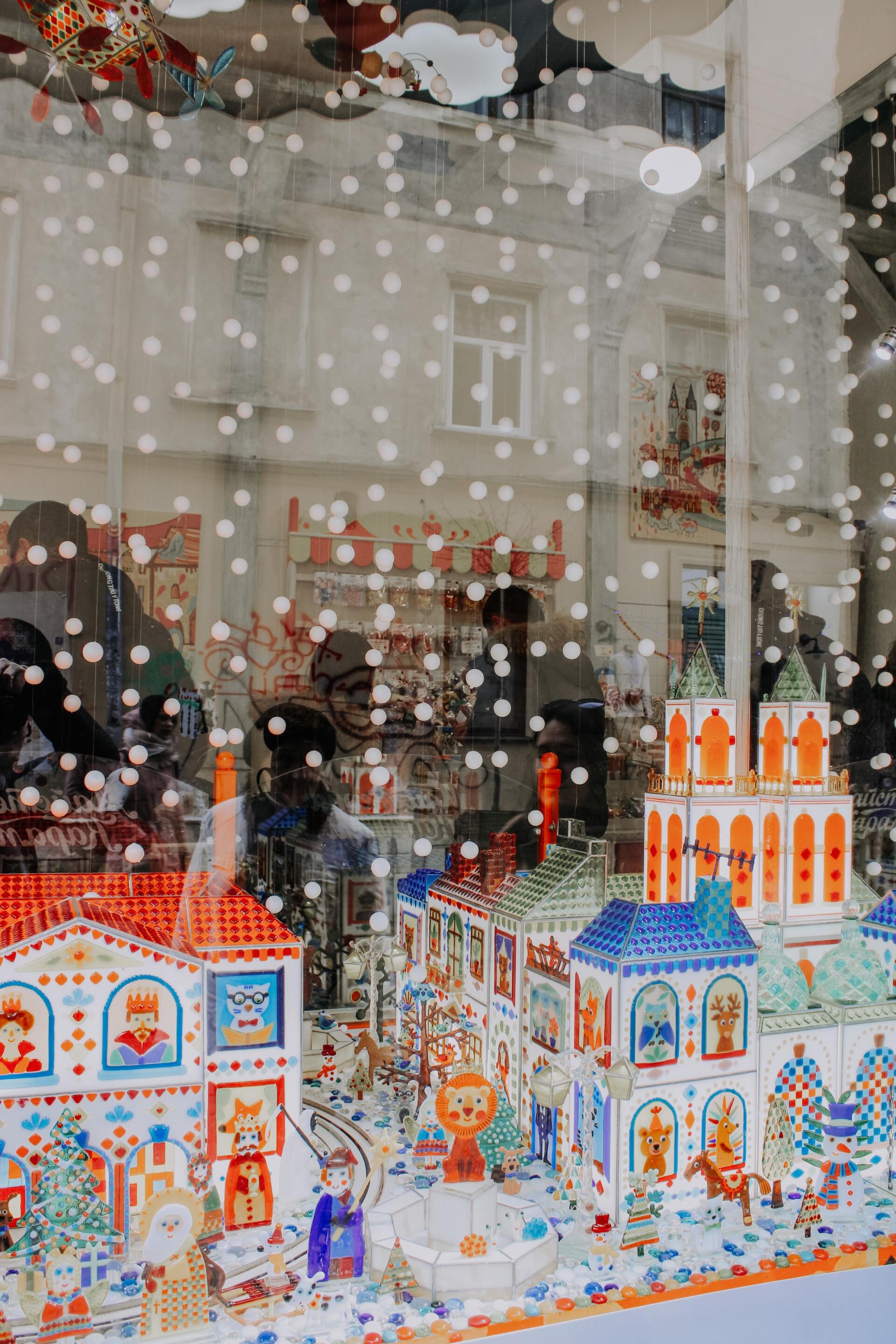 A christmas display in a store window with snow falling on it.