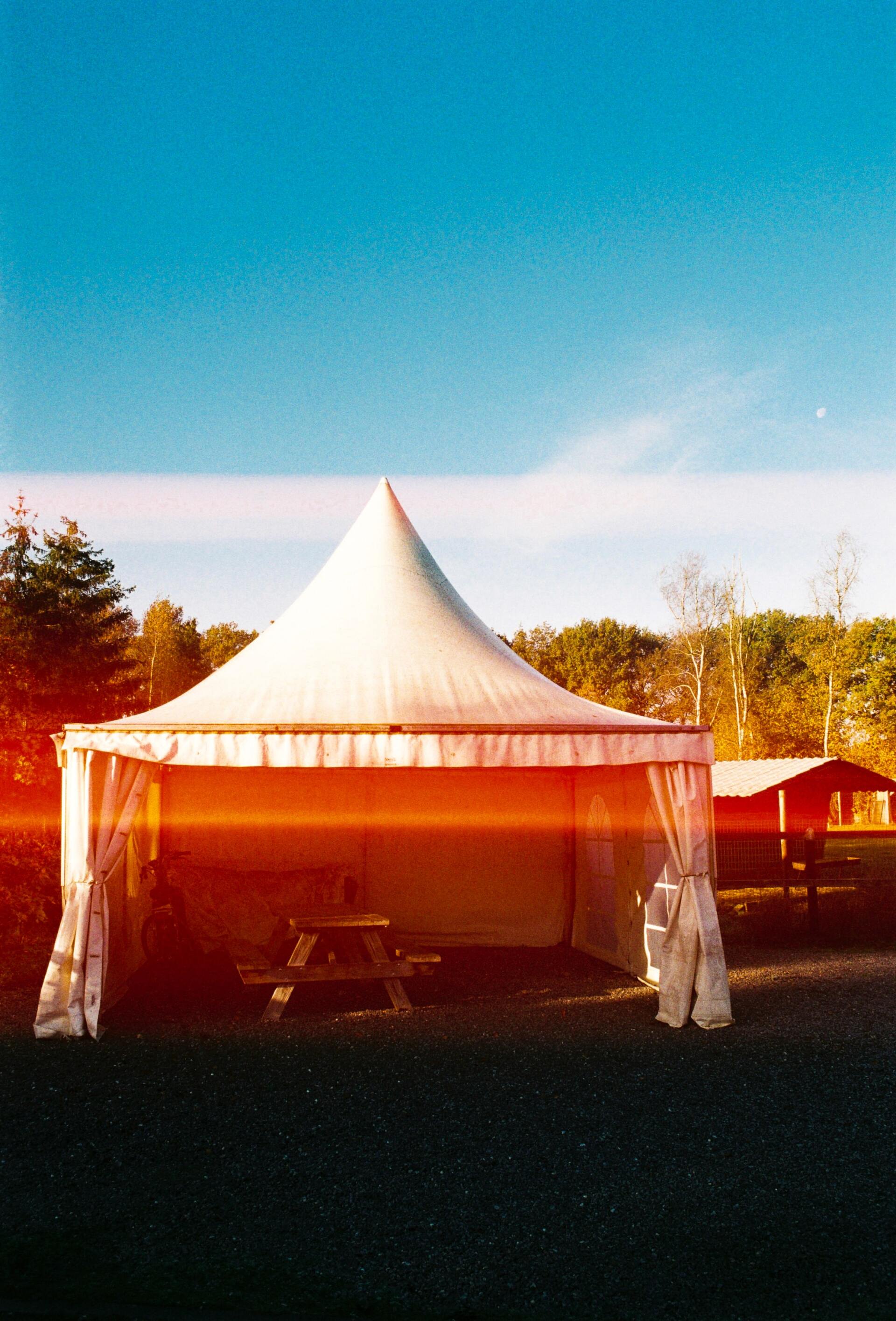 A white tent with a clear roof is in a field