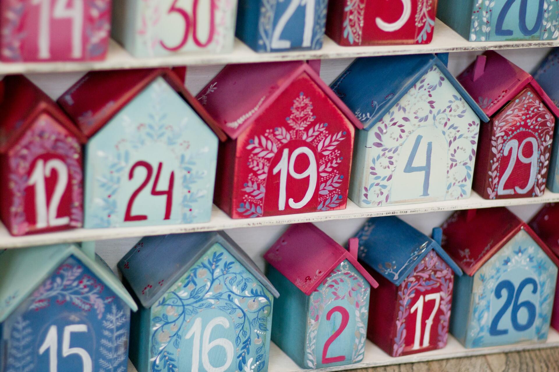 A row of wooden houses with numbers on them are lined up on a shelf.