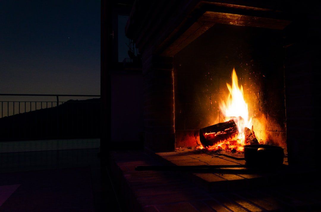 A fireplace is lit up at night with a bottle of wine in it.