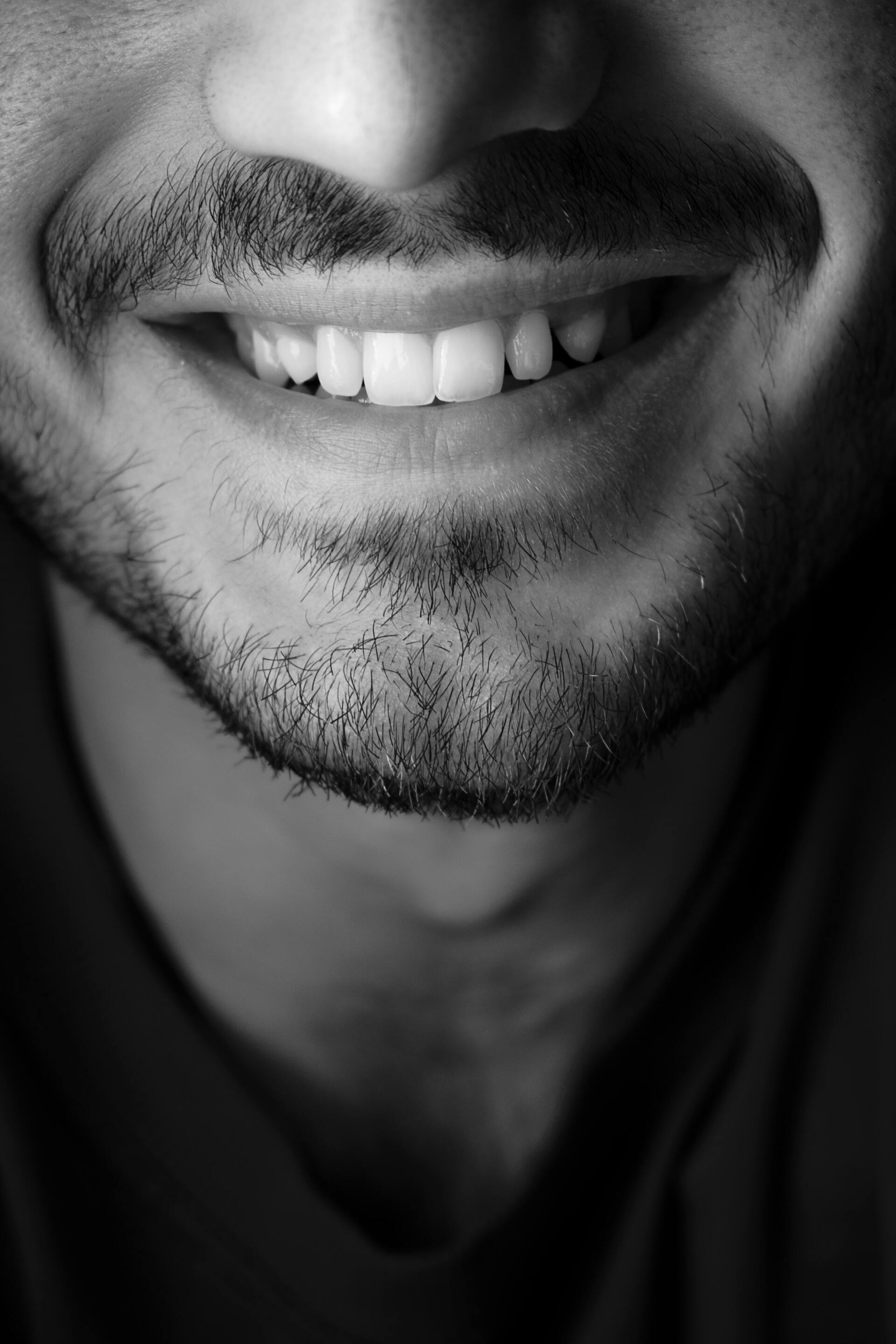 a man with a beard and mustache smiles in a black and white photo