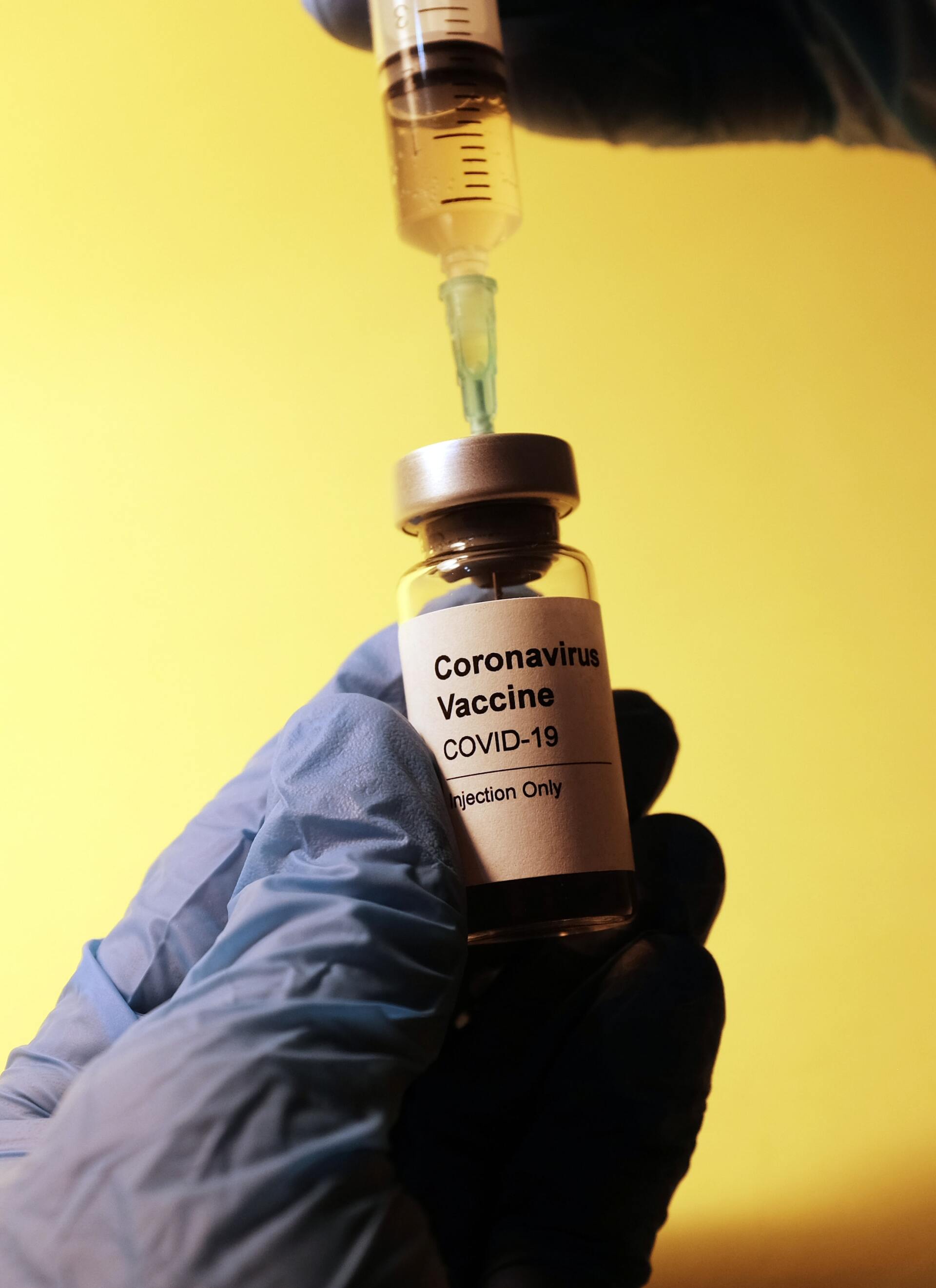 Gloved hand withdrawing dose of COVID vaccine
