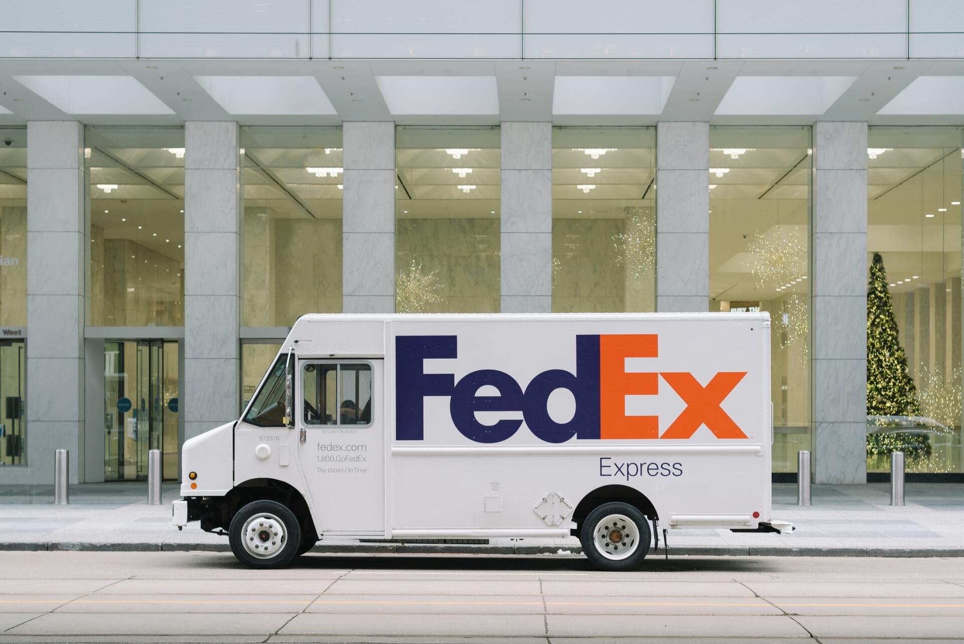 A fedex delivery truck is parked in front of a building