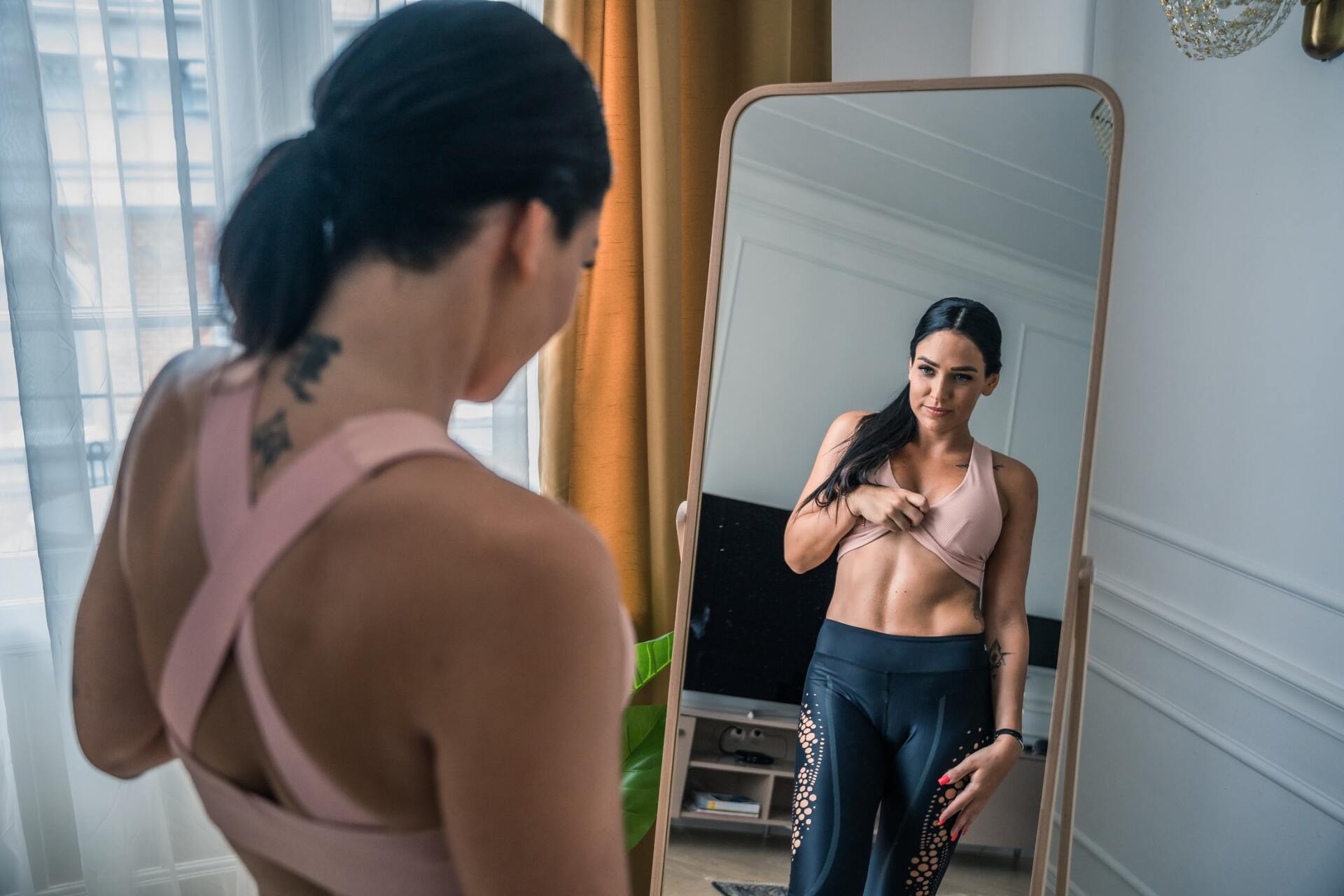 A woman is looking at her reflection in a mirror.