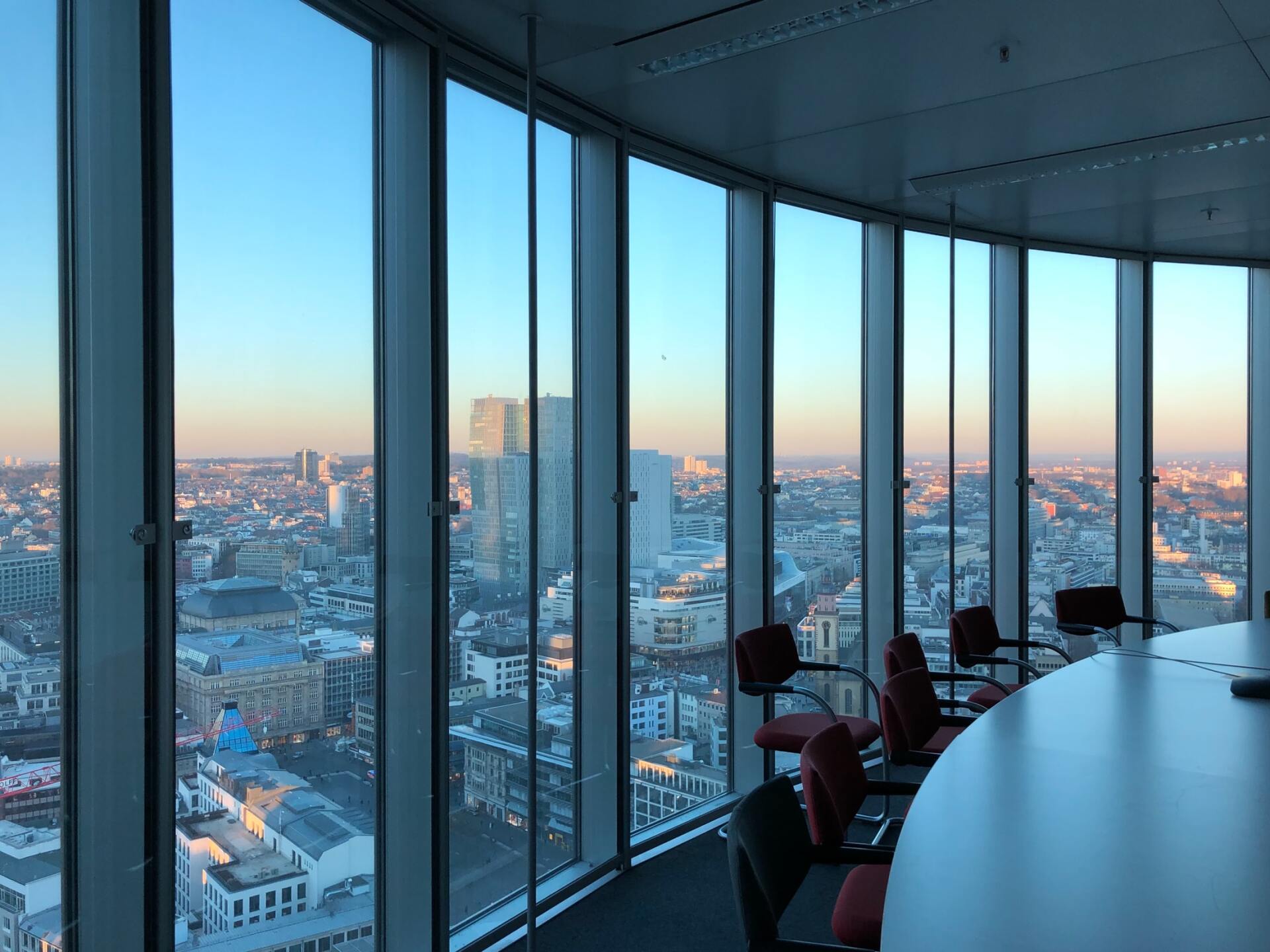 A high-rise office meeting room with large windows showcasing a city view at dusk.