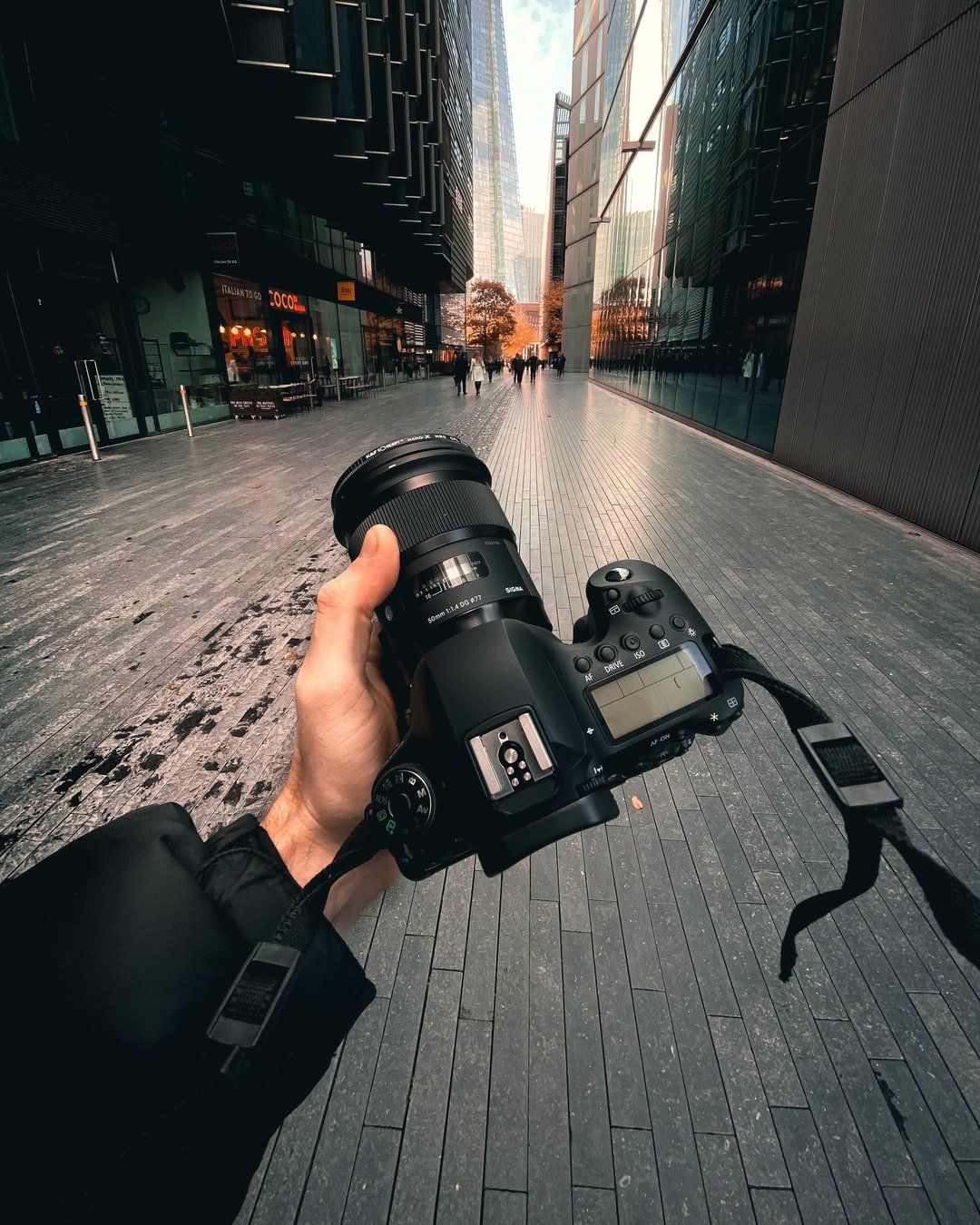a person is holding a canon camera in their hand