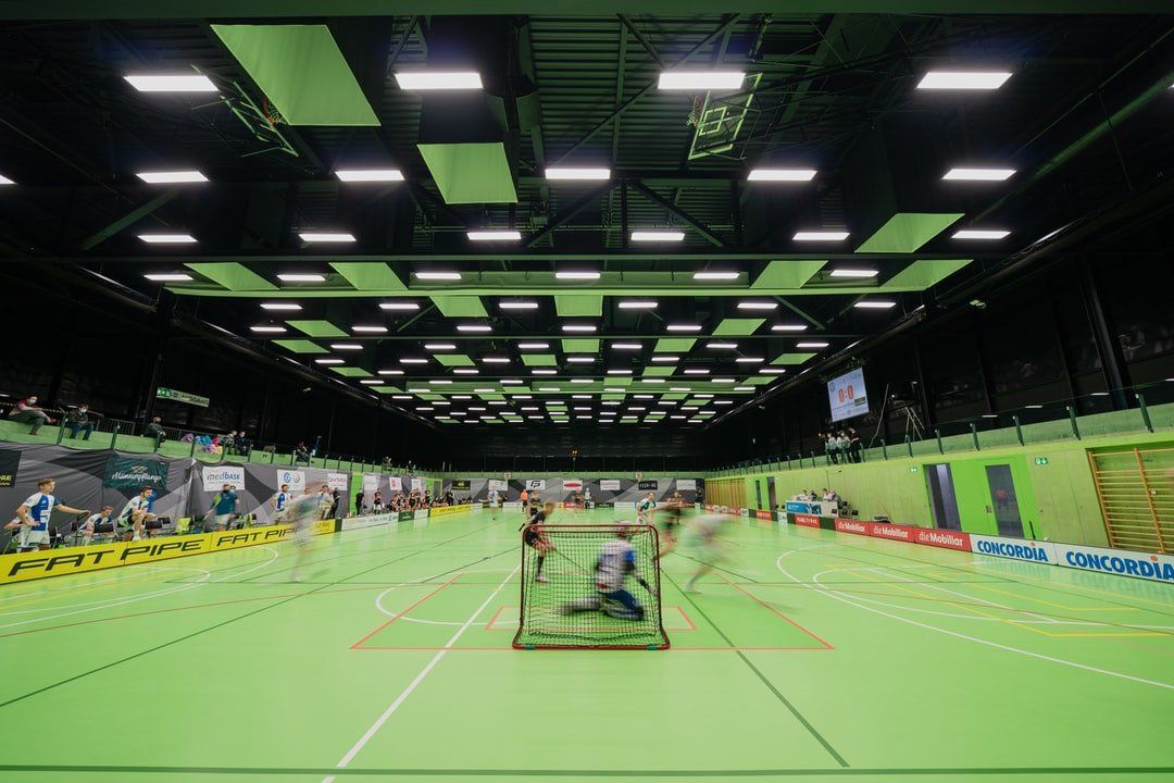 A group of people are playing a game of floorball in an indoor stadium,  commercial heating