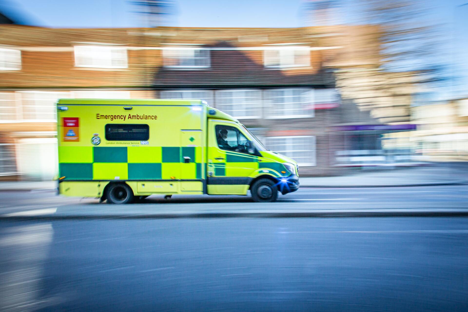 An ambulance is driving down a street in front of a building.