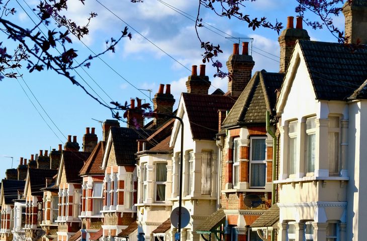 Picture of a row of London town houses. The houses have pitched roofs with chimney stacks and painted render fronts. All the houses have bay windows