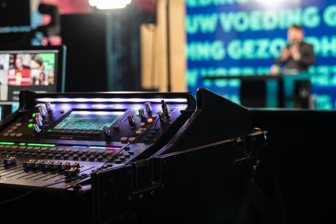 A mixer is sitting in front of a screen with a man in the background.