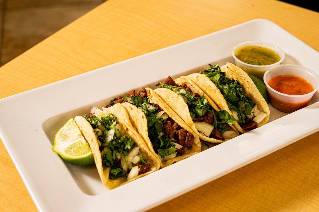 A white plate topped with tacos and sauces on a table.